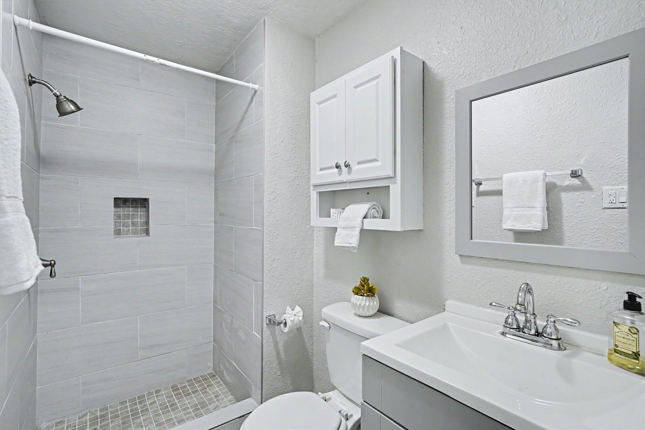 Updated secondary bathroom features a walk-in tiled shower, vanity and additional storage.