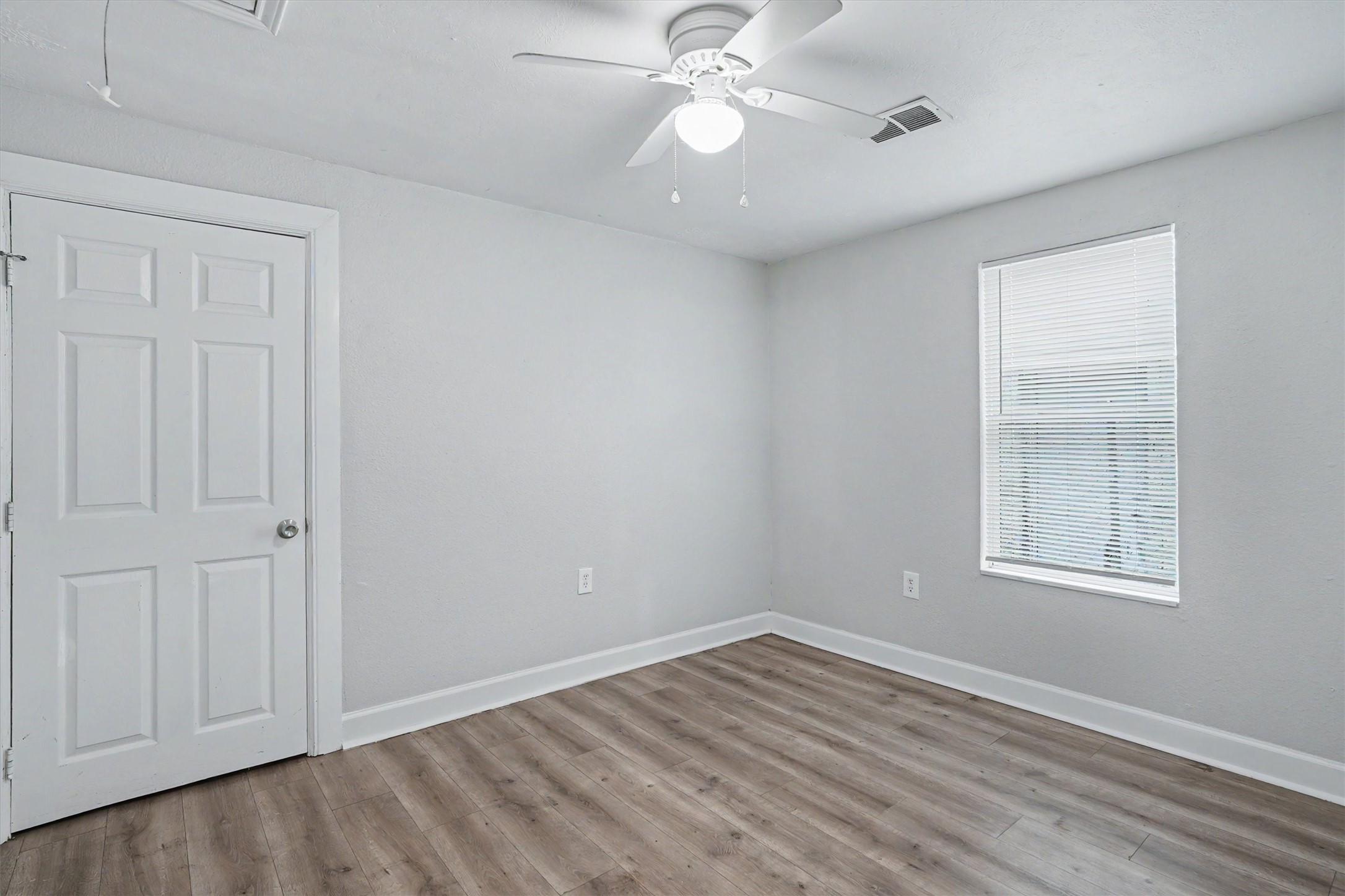 Secondary bedroom with wood-look flooring, fresh neutral paint, ceiling fan and closet.