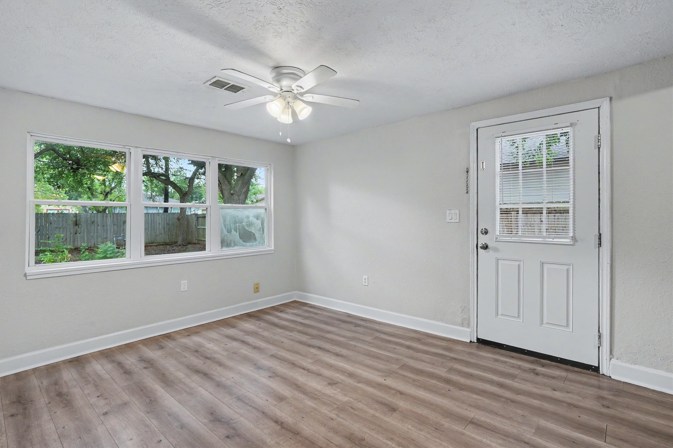 Large windows bring natural light into the living area, with a back door providing convenient access to the yard.