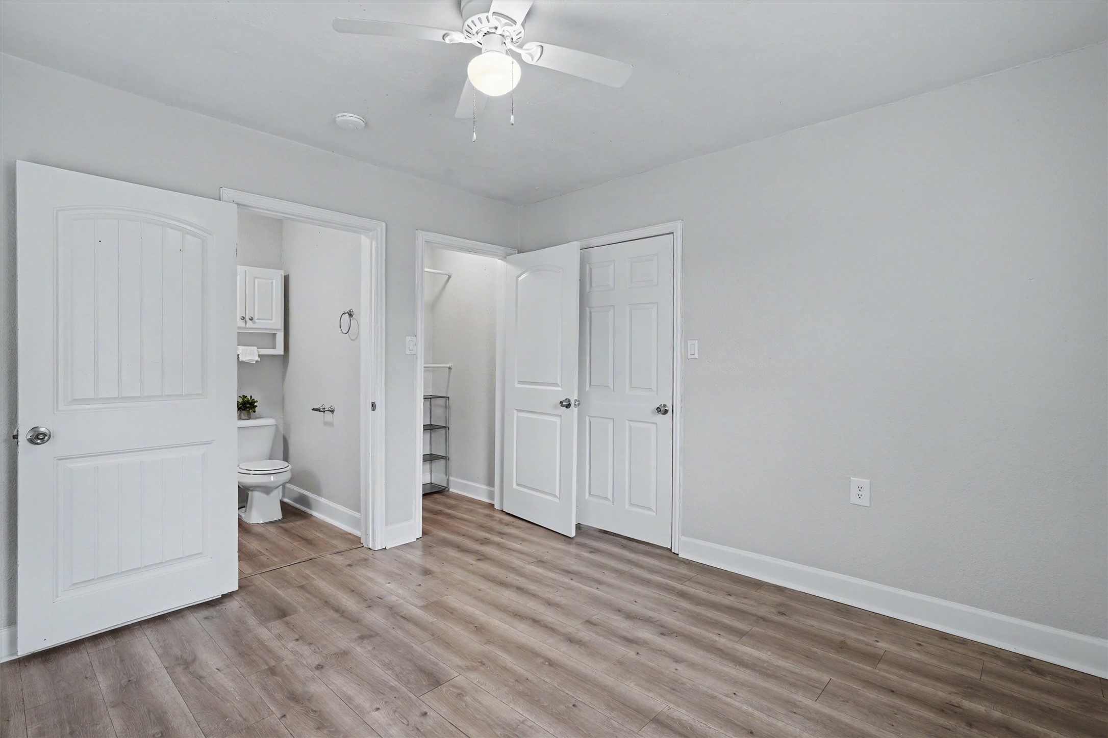 Primary bedroom features an en-suite bath, closet space, ceiling fan and wood-look flooring.