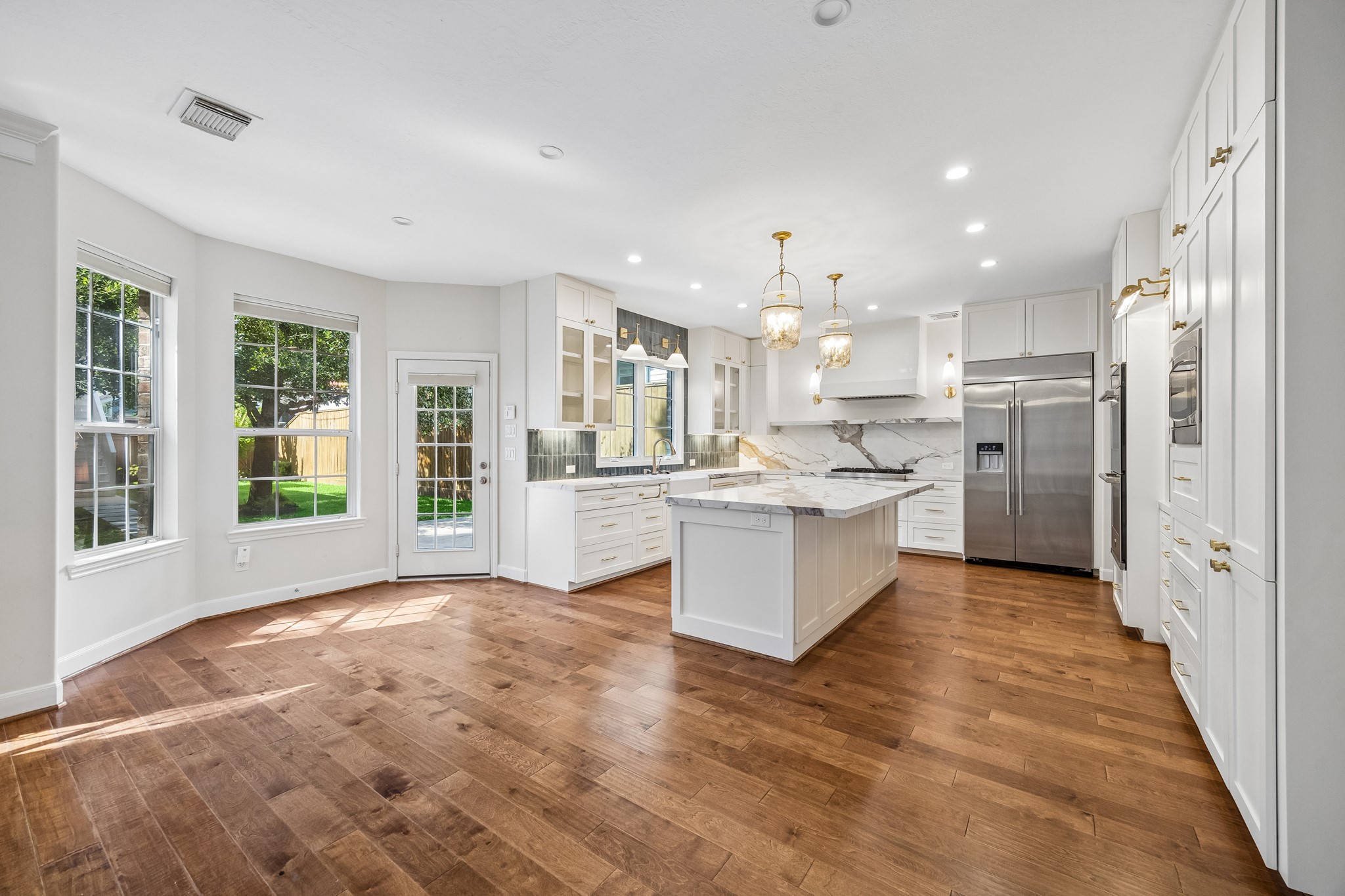 Renovated kitchen with a large center island, quartz countertops and backsplash, custom cabinetry, and stainless steel appliances, opening to the spacious living area. Renovated kitchen with a large center island, quartz countertops and backsplash, custom cabinetry, and stainless steel appliances, opening to the spacious living area.