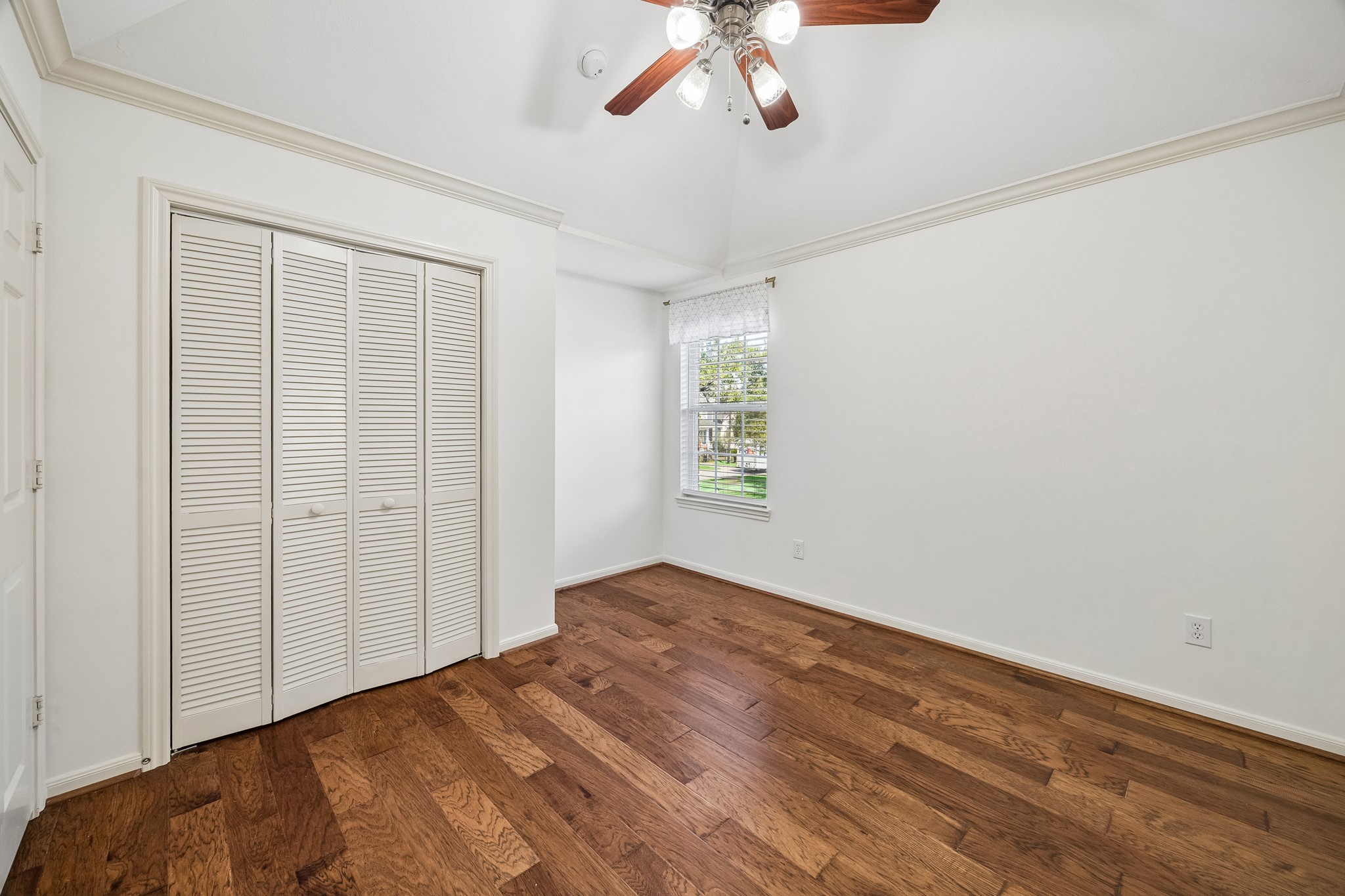 Secondary bedroom with hardwood floors, custom window treatments, and an en suite bath.