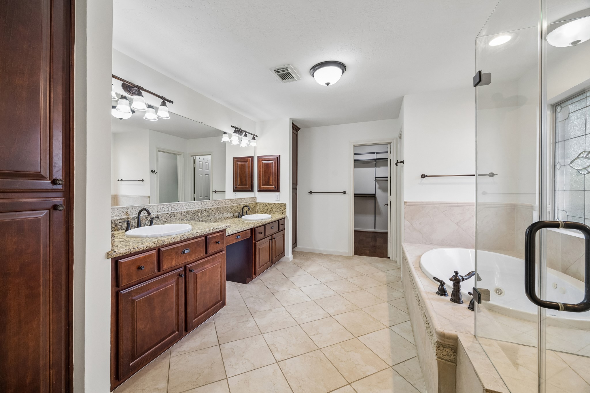 Primary bath featuring dual vanities, an expansive countertop, abundant storage, and a spacious walk-in shower.