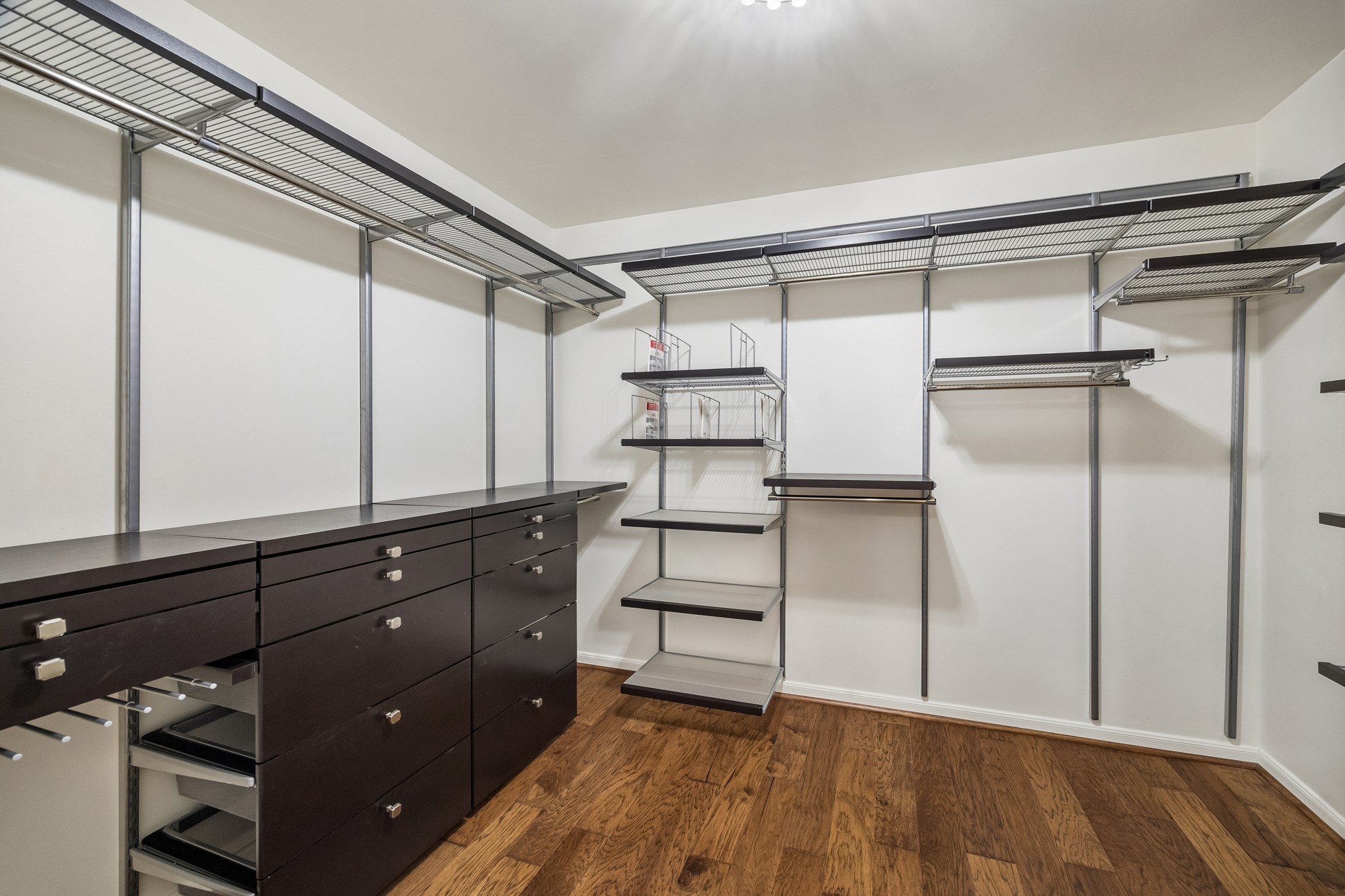 One of two primary walk-in closets, featuring an extensive custom organization system with open shelving, hanging space, and drawers.