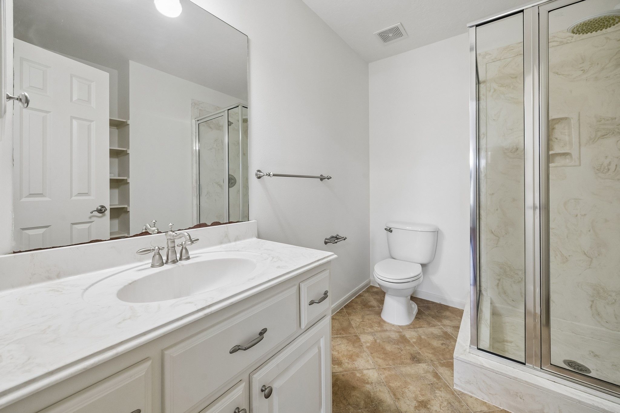En suite bath with a dual-sink vanity, generous counter space, and a spacious walk-in shower with contemporary tile finishes.