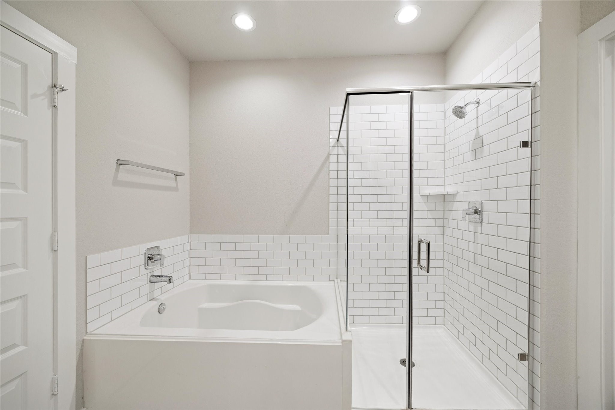 The bath includes a soaking tub paired with a glass enclosed shower, offering both relaxation and convenience. Subway tile and clear glass keep the design light and classic, while durable finishes support everyday living.