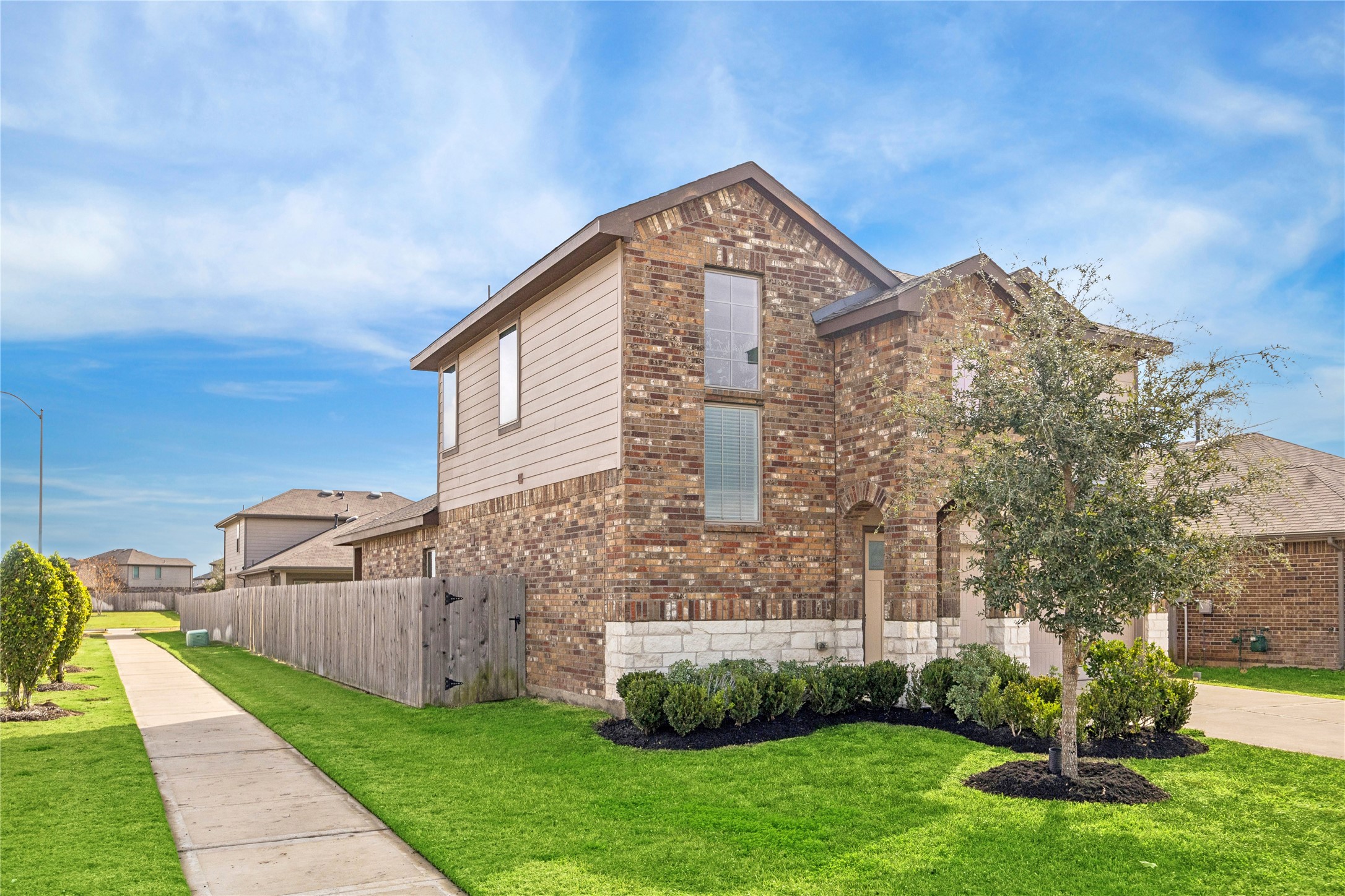 Classic brick exterior paired with stone accents creates strong curb appeal from the moment you arrive. Fresh landscaping, manicured lawn, and a private side gate add both charm and everyday convenience.