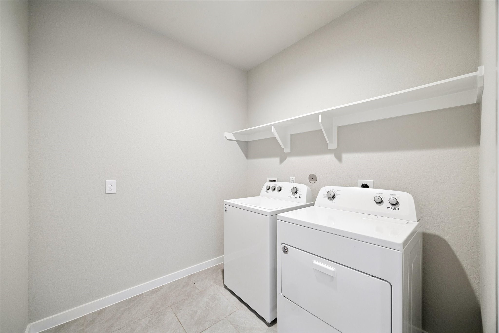 A dedicated laundry room offers a practical, organized workspace with room for full-size appliances and additional storage. Durable flooring and a clean, efficient layout support everyday living while keeping utility spaces thoughtfully separated from main living areas.