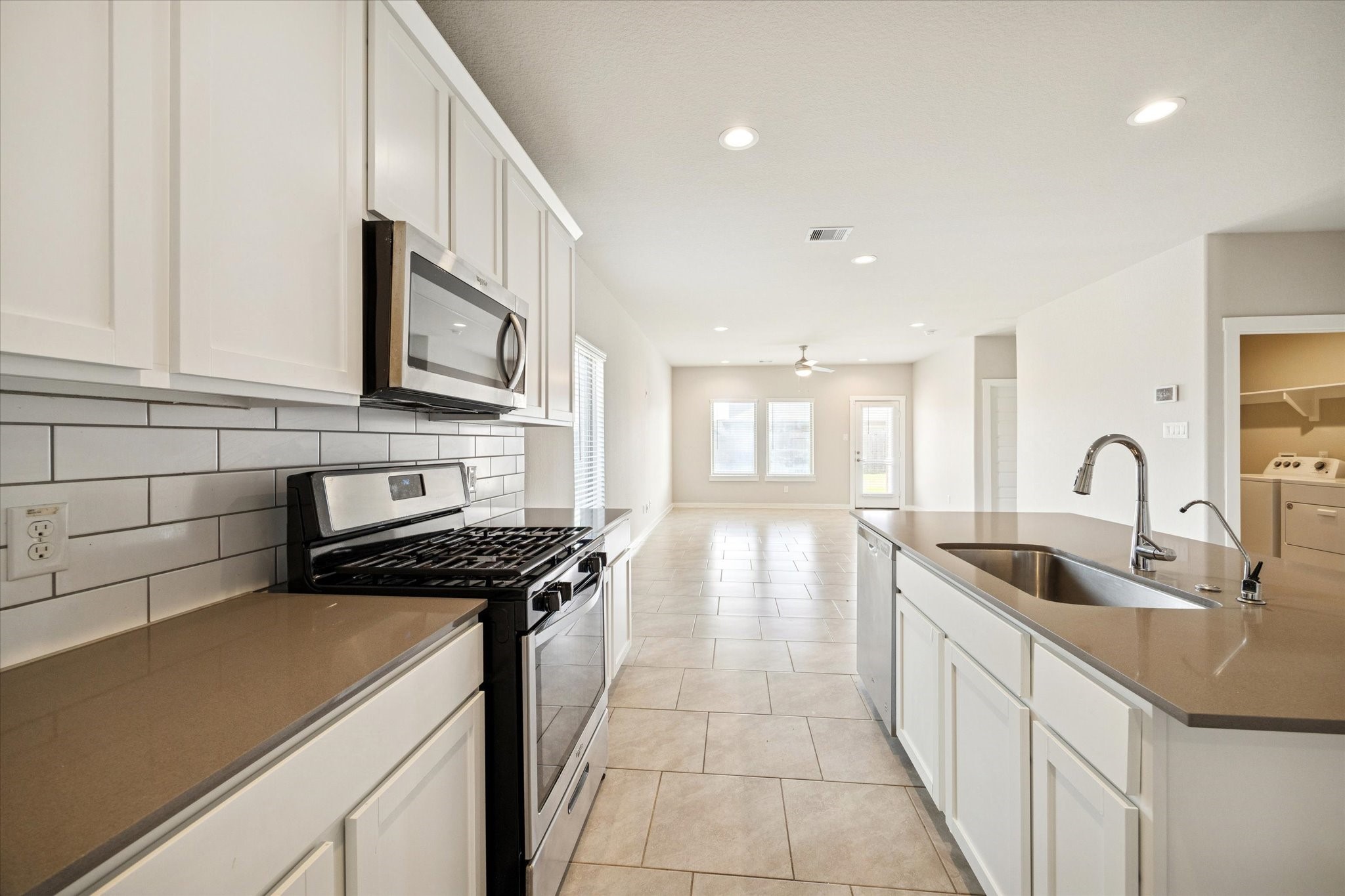 Gas range and built-in microwave pair with generous counter space, offering an efficient cooking layout framed by crisp white cabinetry.