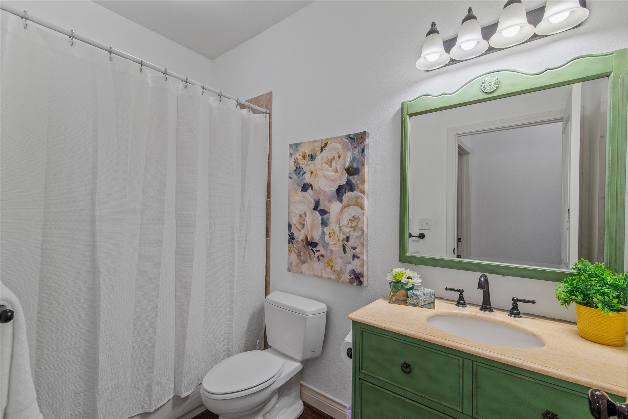 Privately tucked away near the flex room and additional bedrooms, this full bathroom features a tub/shower combination and a charming green vanity with coordinating mirror.