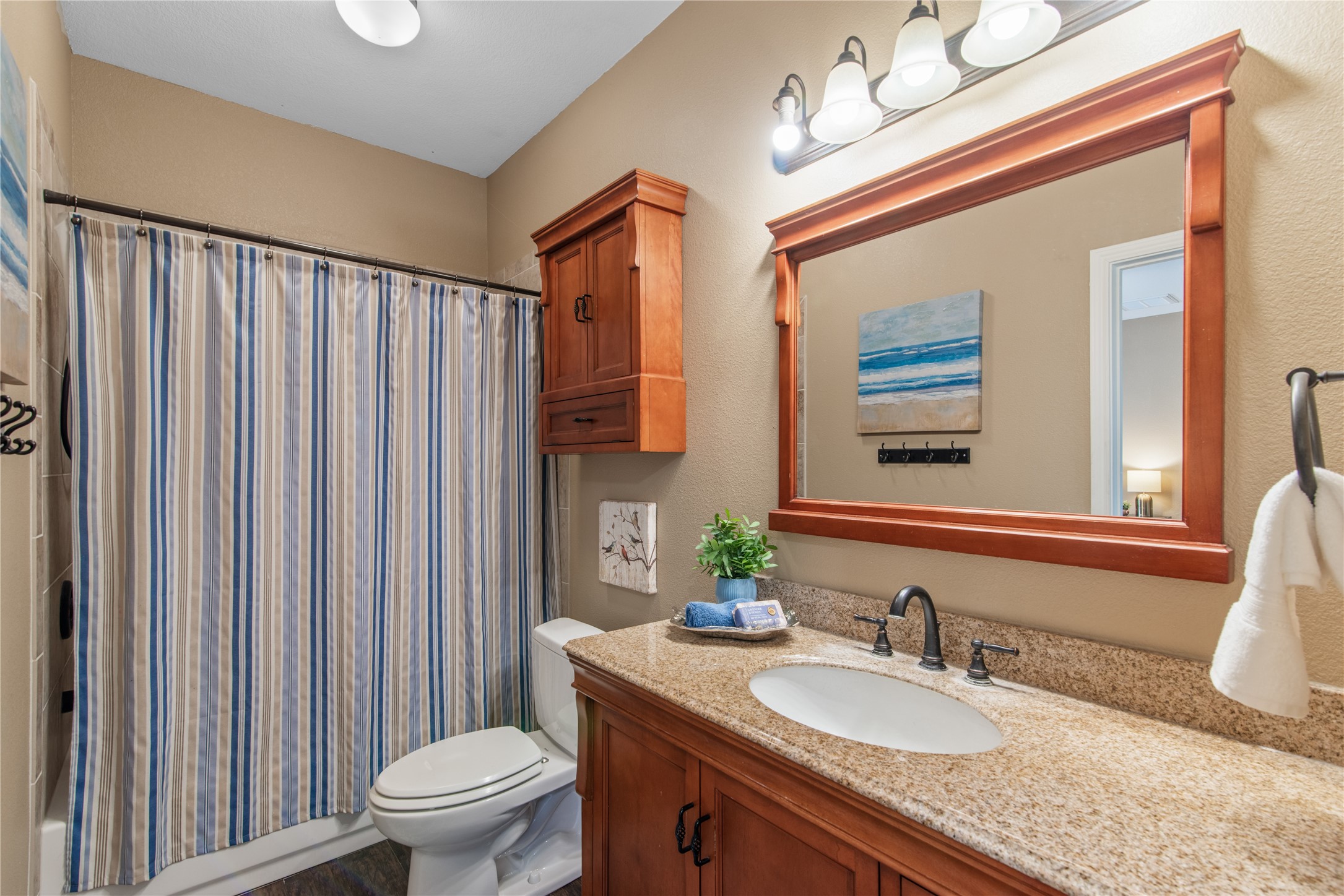 Jack-and-Jill bathroom connecting two secondary bedrooms, featuring a tub/shower combination, a spacious vanity, and coordinating wood cabinetry for added storage.