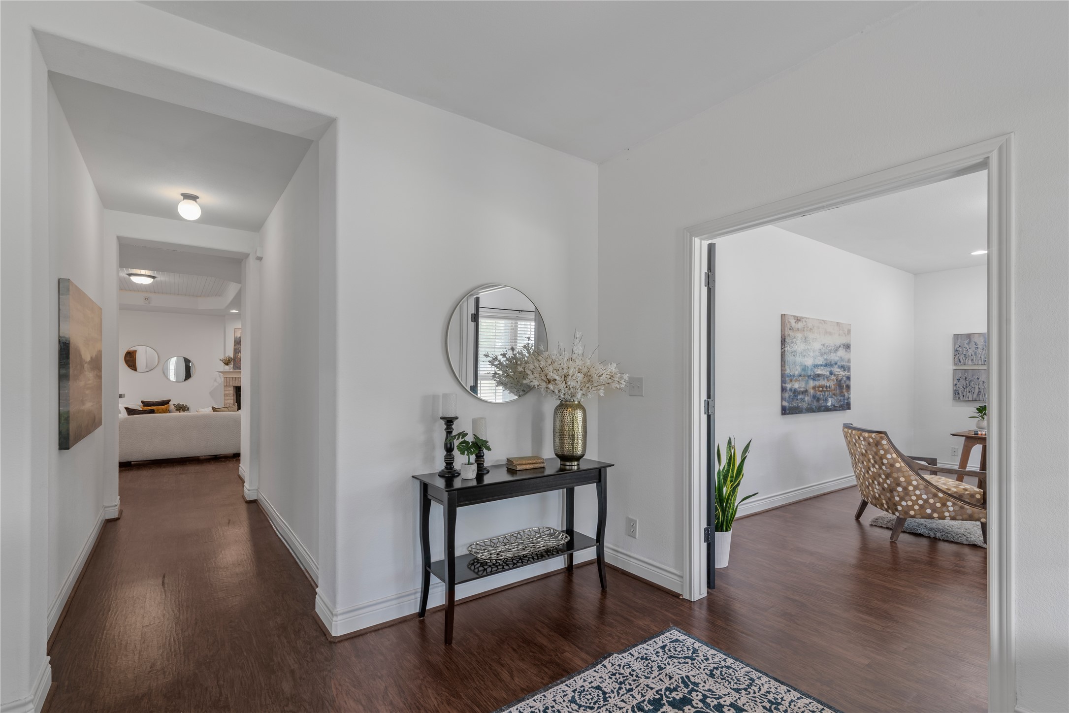 Welcoming entry with high ceilings and rich wood-look flooring, offering access to the home office and a glimpse of the family room beyond.