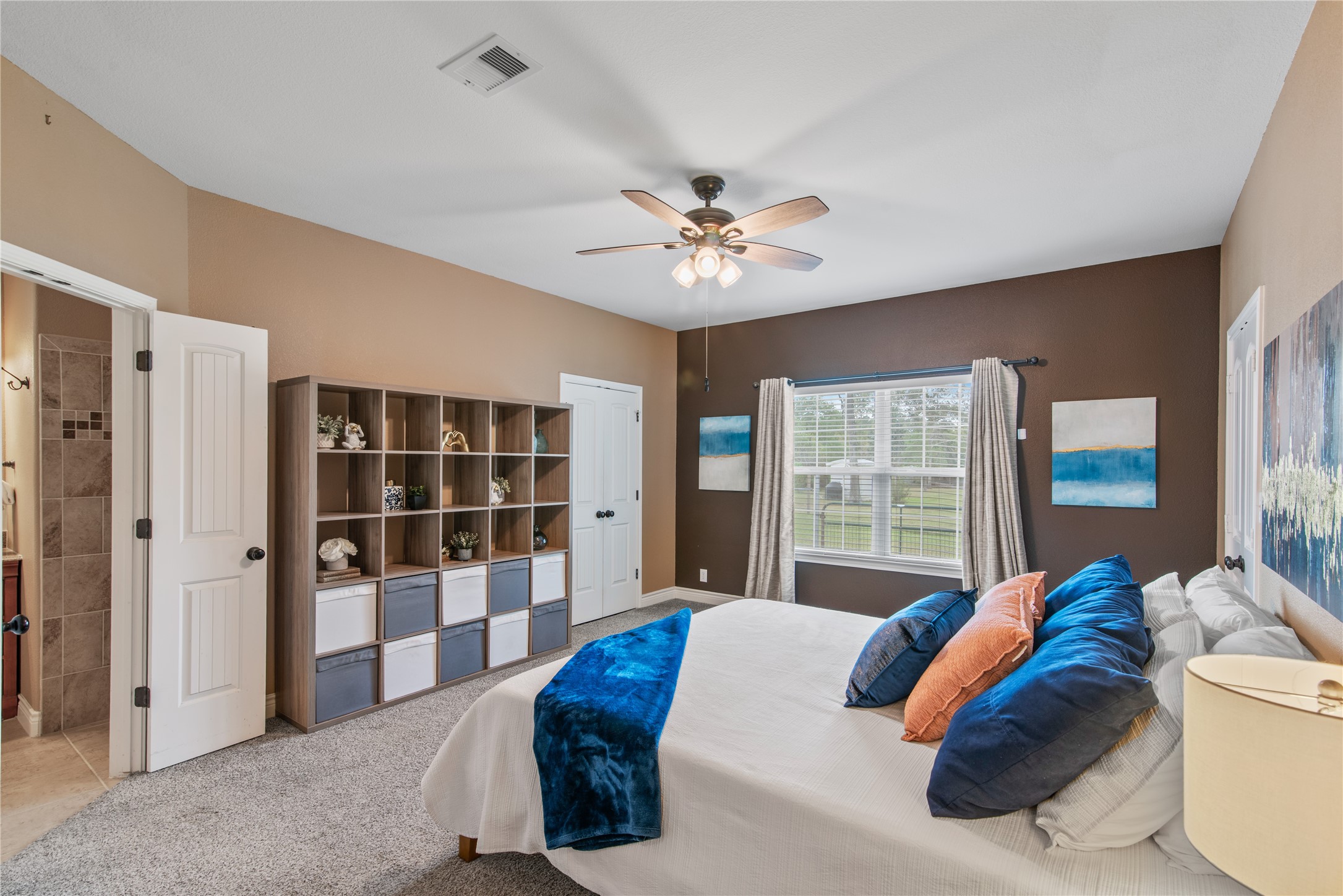 Spacious primary bedroom featuring high ceilings, a large window, and a private en-suite bath, complemented by two walk-in closets for generous storage.