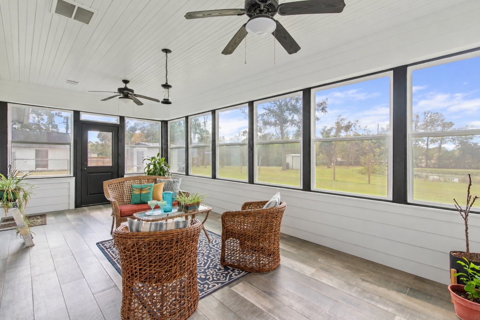 Generously sized sunroom with plenty of space for multiple seating areas, perfect for relaxing or gathering with guests while enjoying backyard views.