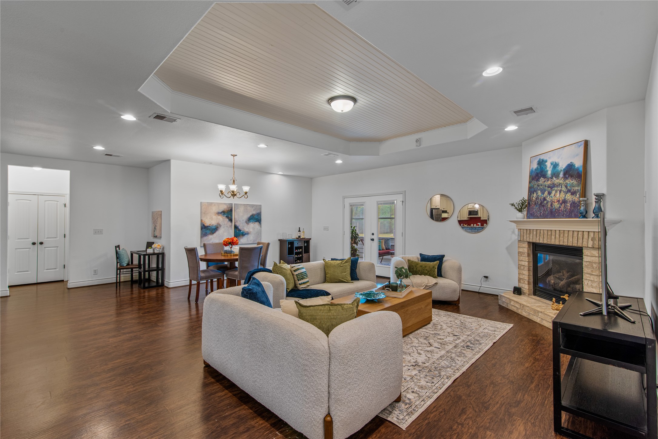 Spacious family room featuring a distinctive tray ceiling with beadboard detailing and a brick fireplace, creating an inviting gathering space.