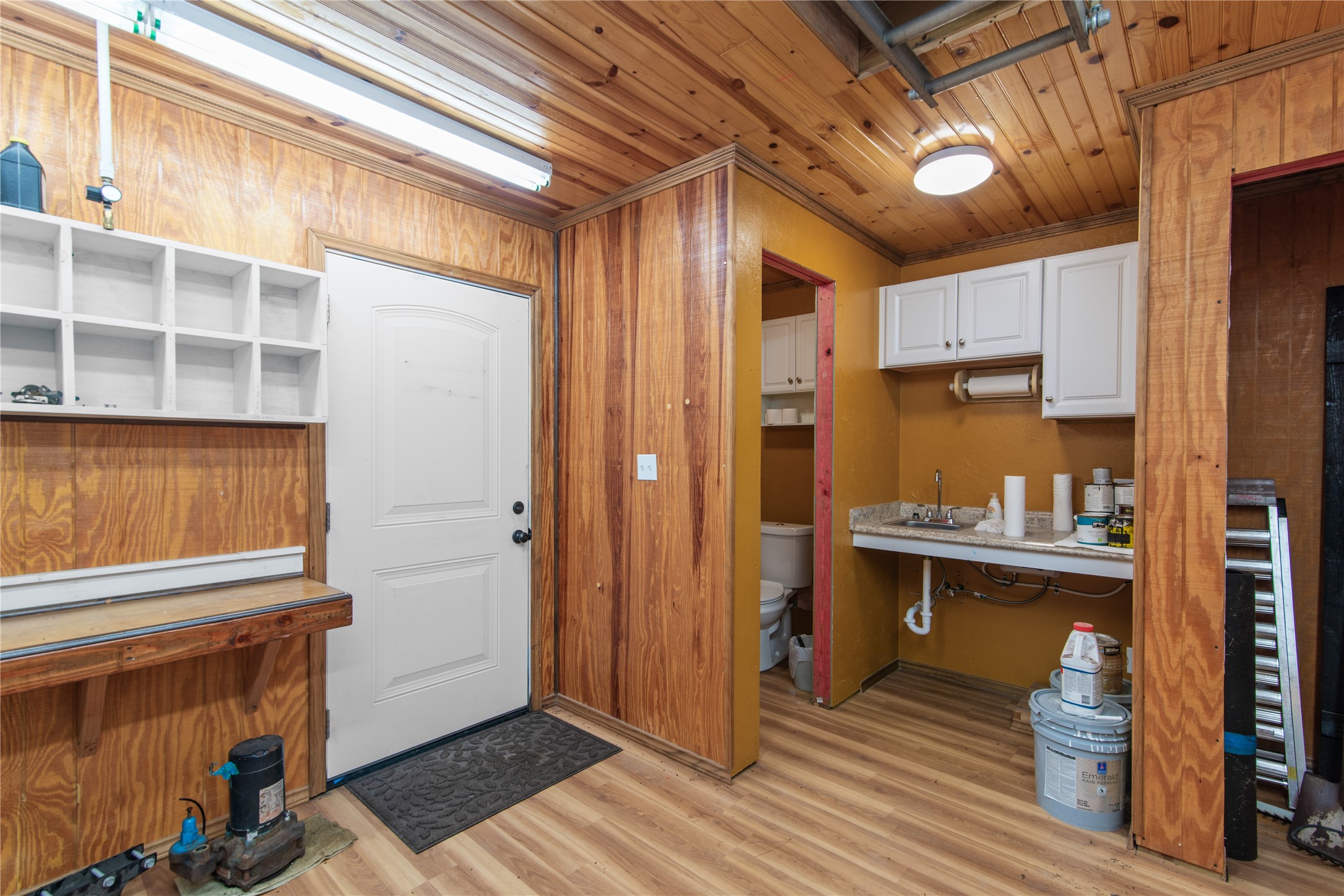 The workshop also includes a convenient sink, overhead cabinetry, and a separate toilet area for added functionality.