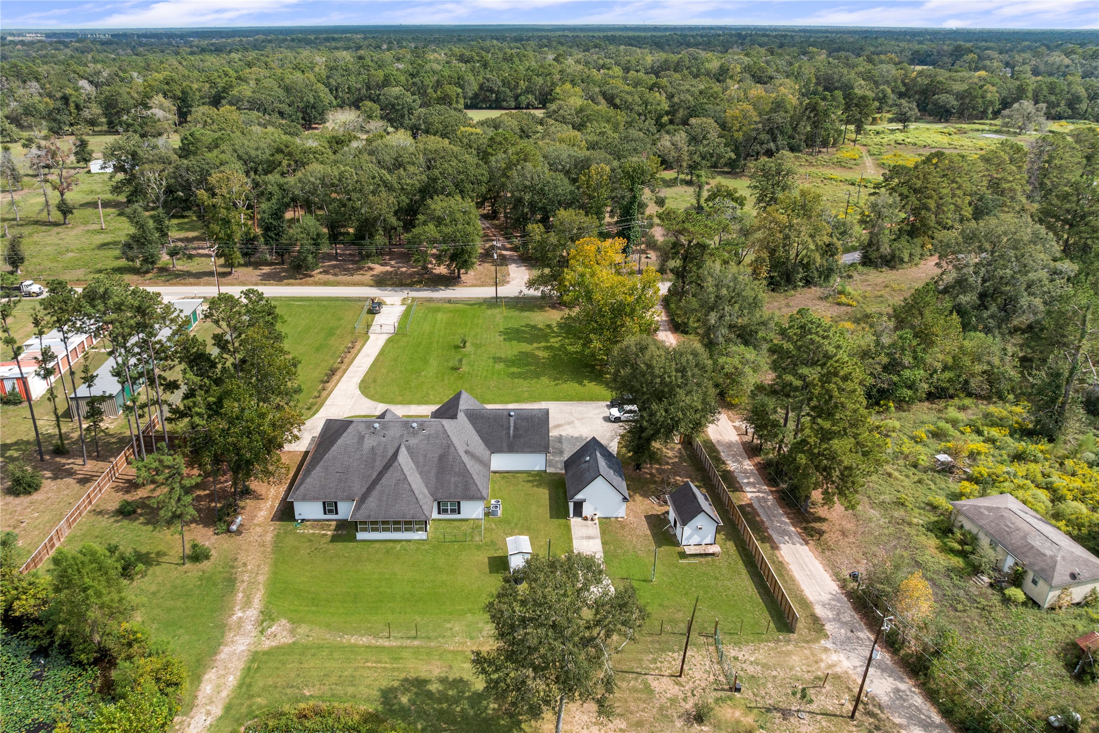 Aerial view showcases the homes placement on 1.77 acres, with an extended driveway, detached garage, workshop, water well house, and generous outdoor space.
