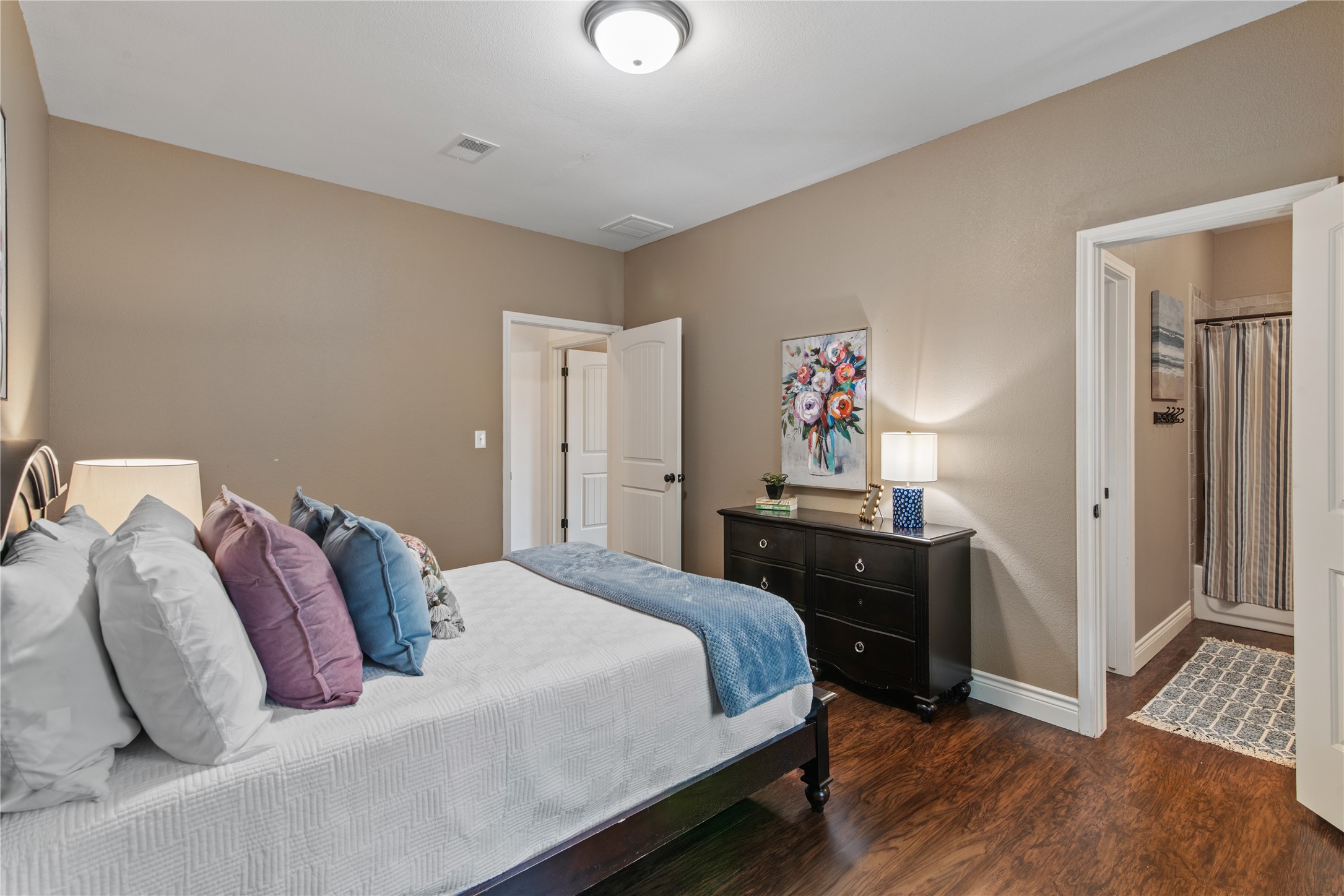 High ceilings, warm neutral tones, and wood-look flooring create an inviting secondary bedroom with plenty of room for additional furnishings.