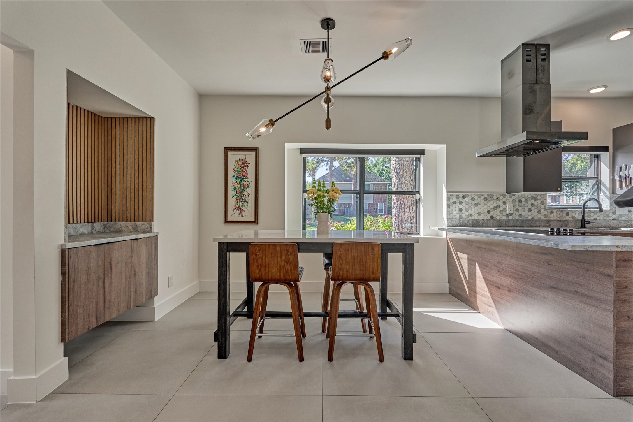 Sunny breakfast room offers statement chandelier, bonus floating cabinetry with paneled accents for additional storage, and adjacent bar area for added seating options if desired.