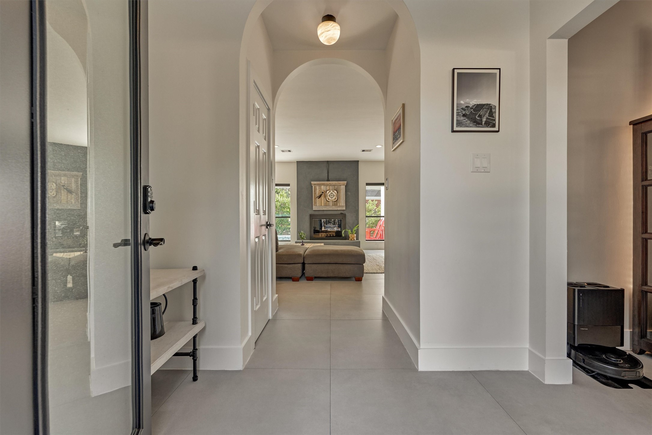 Welcoming foyer showcases the chic design elements of this reimagined home including arched doorways, fresh interior paint, continuous tile flooring throughout the main living area and upgraded lighting.