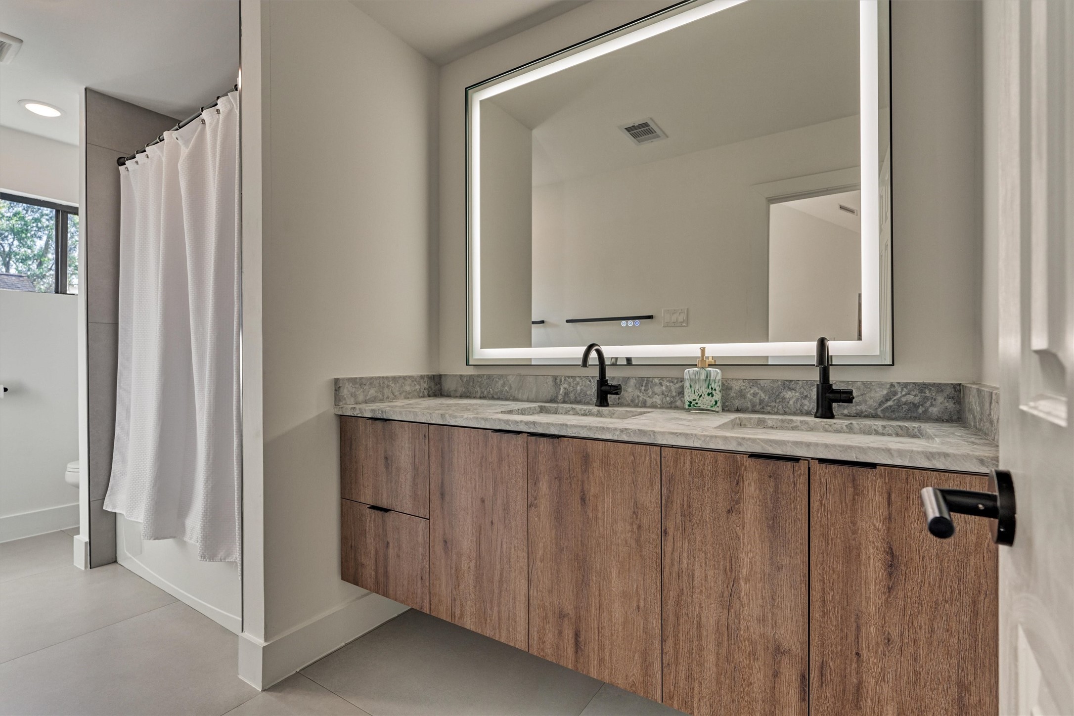 Spacious full bath with lighted mirror, floating dual sink vanity, and tub/shower combo flawlessly serves the upstairs.