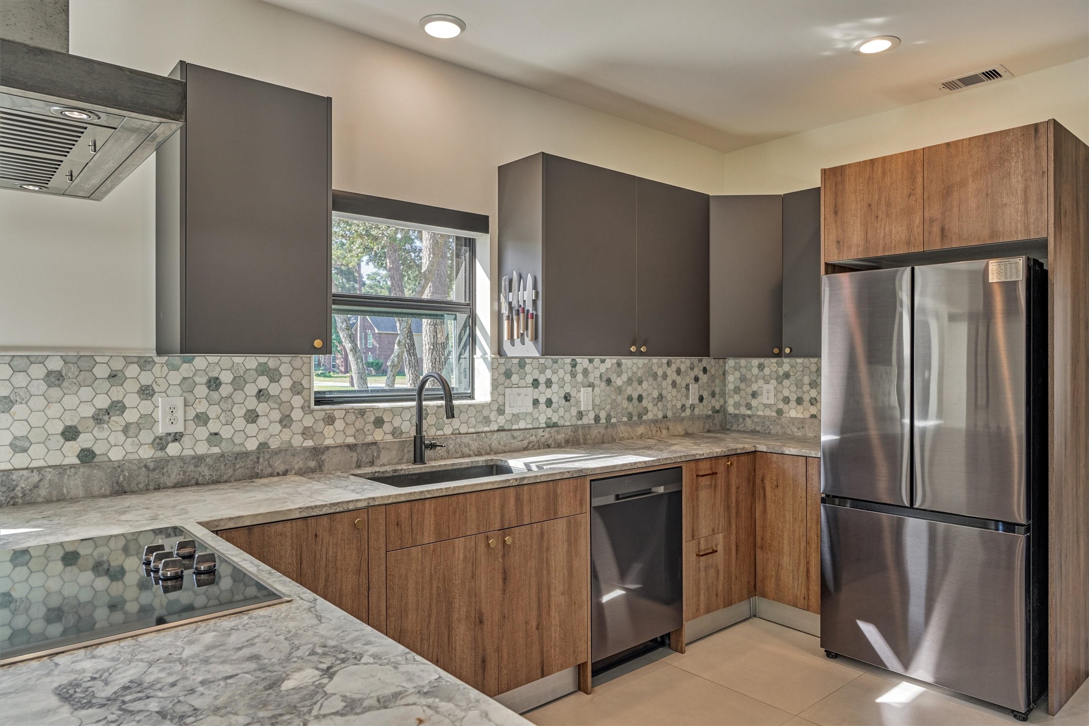 LED lighting throughout this home upgrades the space to complete the clean, modern aesthetic. Note the stainless appliance package and sleek cooktop.