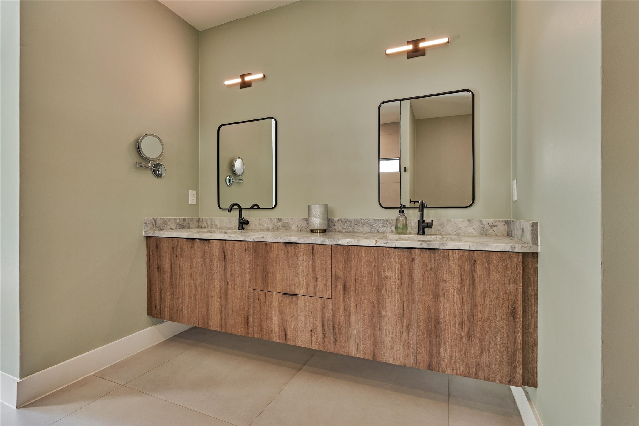 Floating vanity with elevated lighting and hardware offers ample storage in this primary bath.