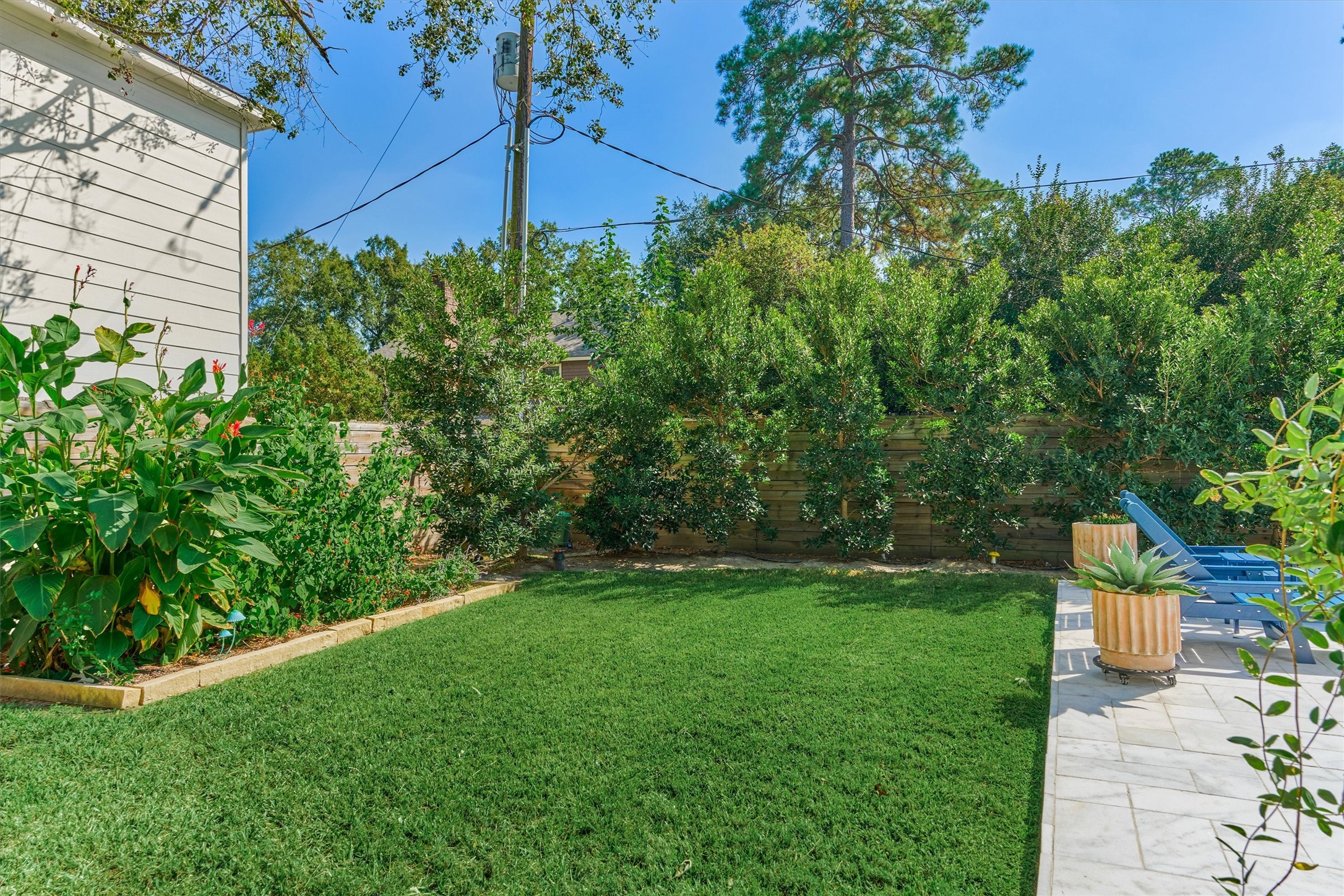 Raised garden beds with soaking hose adorn the fence line in this private backyard.