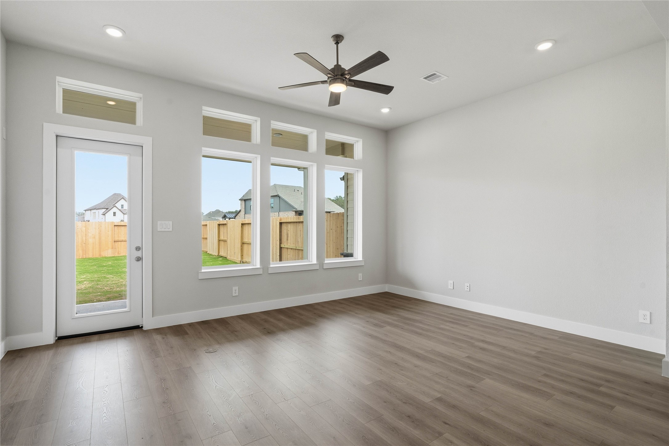 Soaring, tall windows frame the living space, bathing the room in natural light and highlighting the architectural volume of the space. A convenient back door provides direct and easy access to a comfortable covered patio, effortlessly extending your living space outdoors for year-round enjoyment and entertaining.