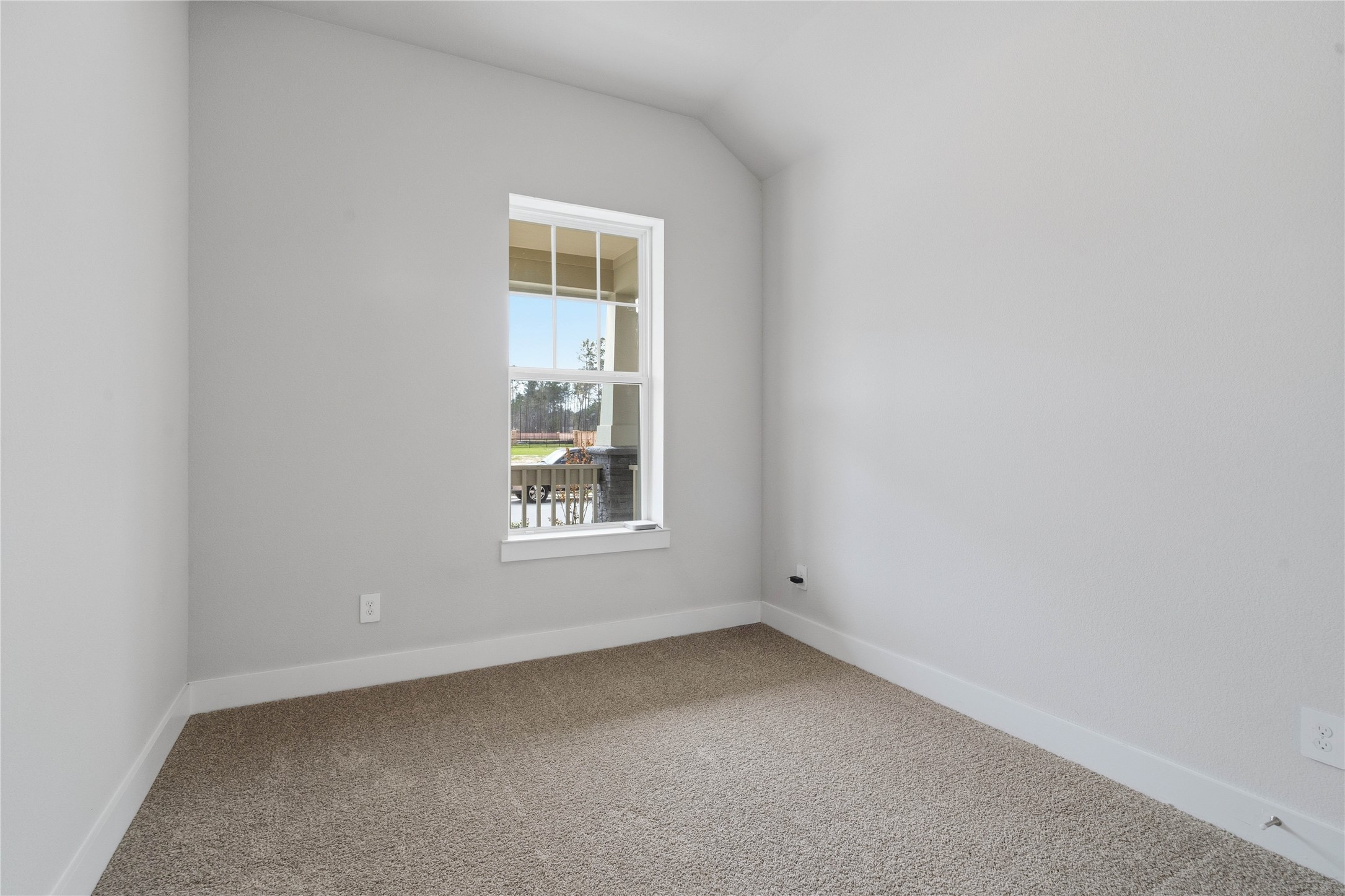 Step into this bright and airy secondary bedroom which features plush carpet flooring, ample sized closet space, and a large window which illuminate the room's sloped ceiling and neutral tones, creating a cheerful and airy environment.