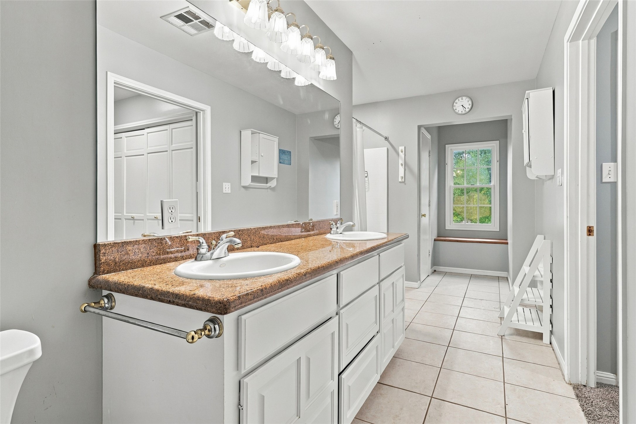 Highlights of this primary bath include a stylish double-sink vanity, a large shower, and convenient extra storage.