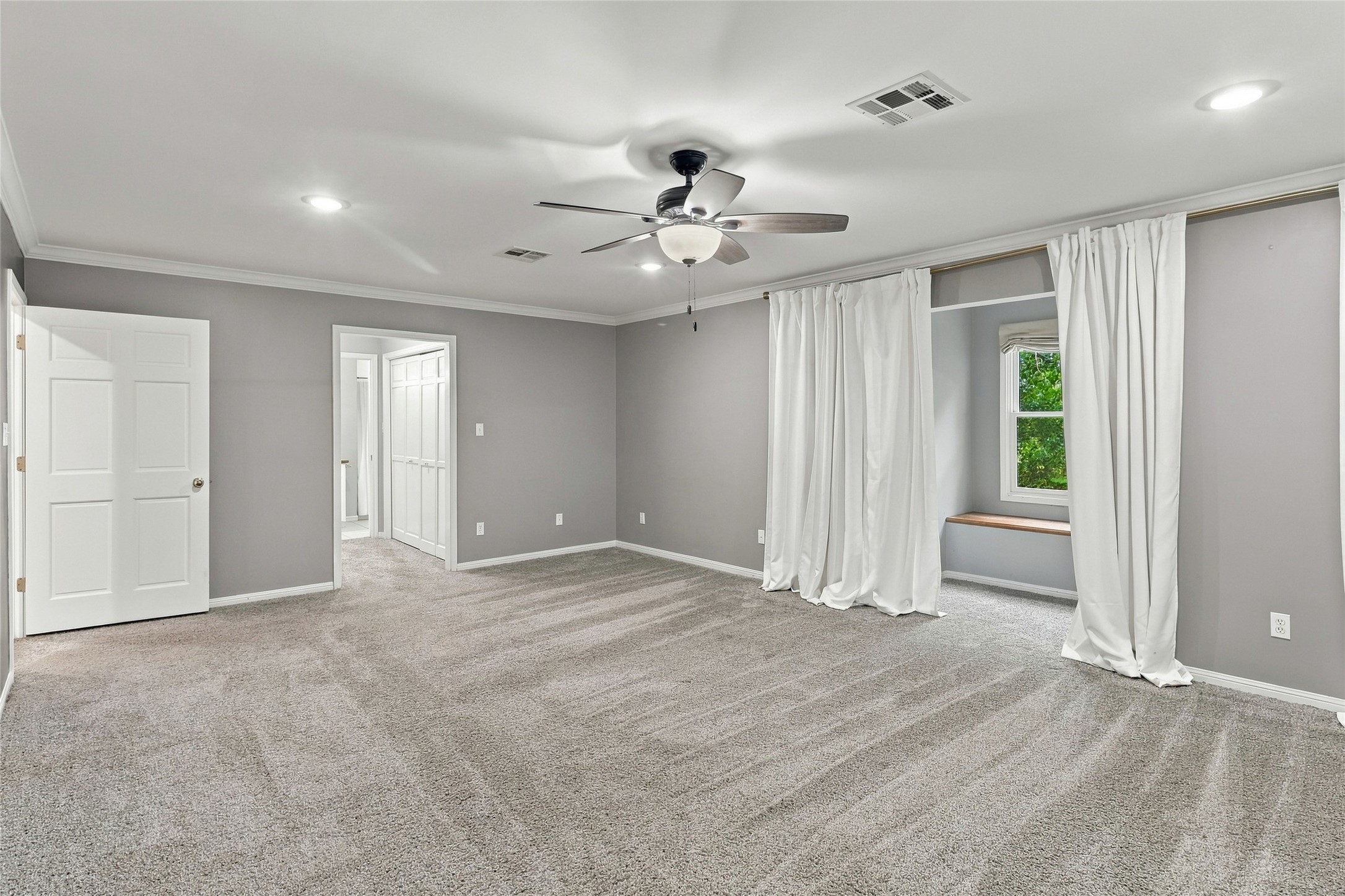 This bright, airy primary bedroom offers ample space to unwind.