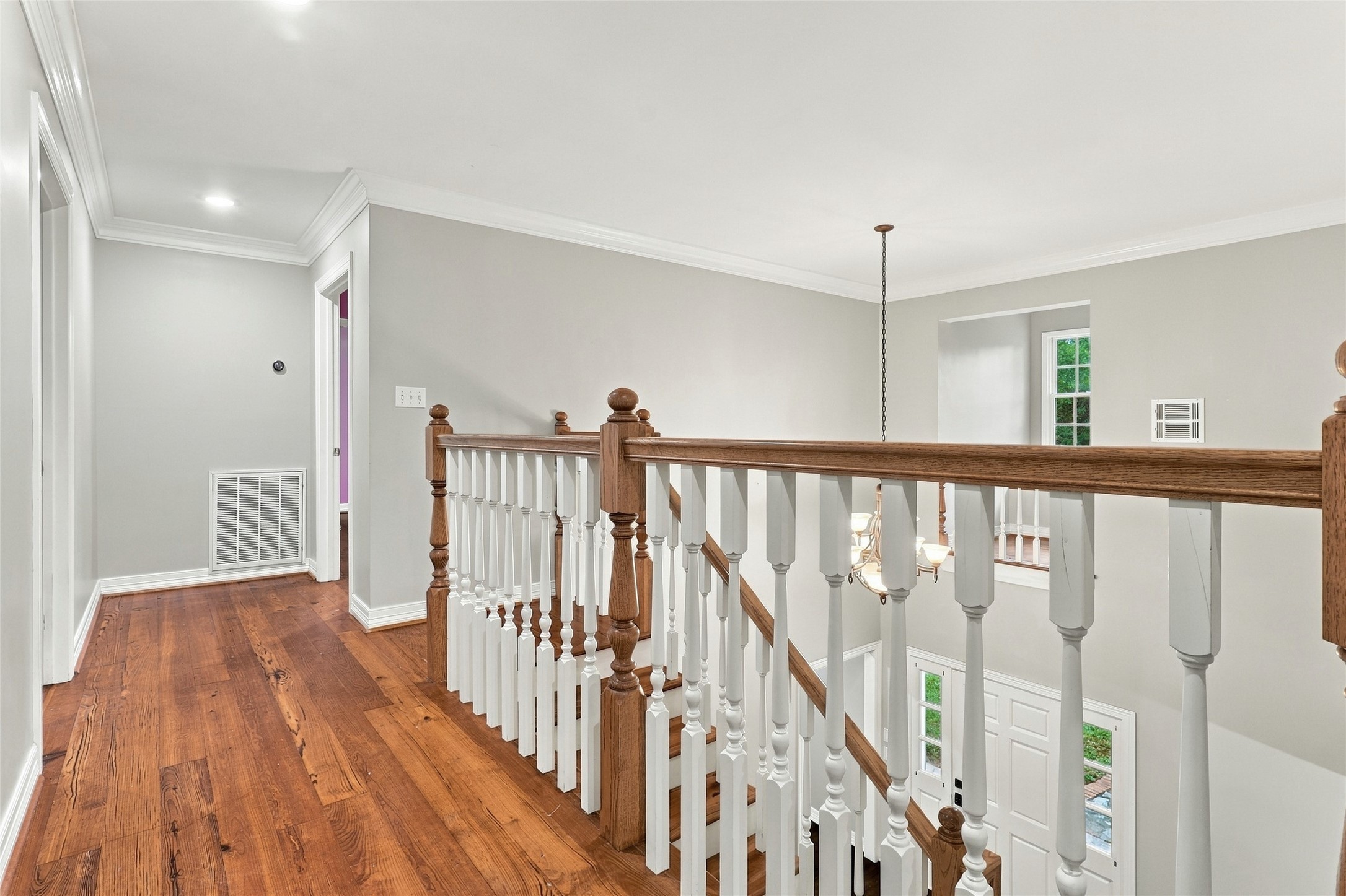 Bright, light-filled upstairs hallway features beautiful wood laminate flooring.