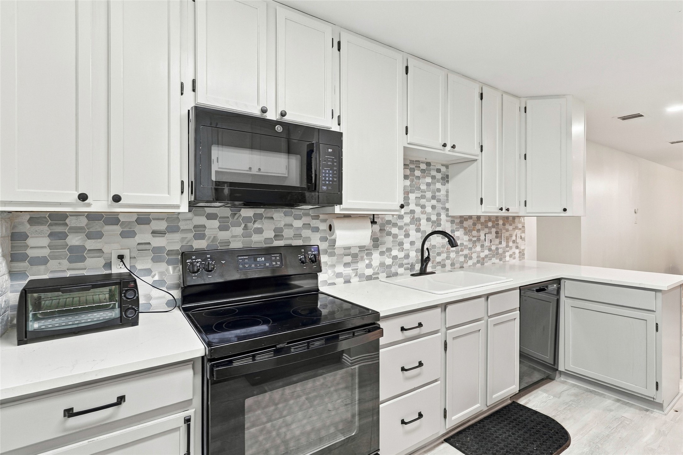 Another angle of this stylish garage apartment kitchen, complete with modern appliances, ample counter space, and decorative backsplash.