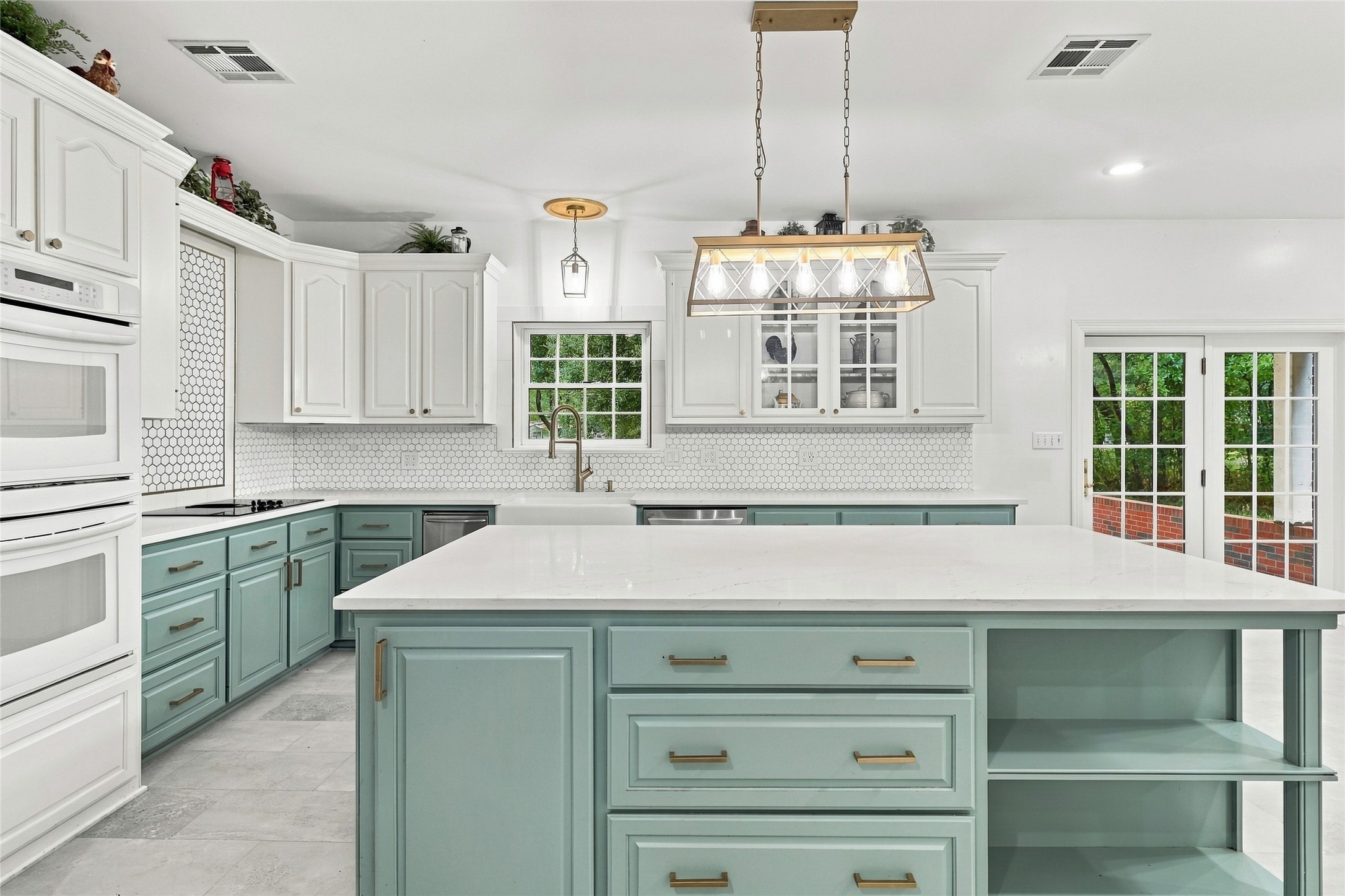 This kitchen is a chef's dream, featuring stunning two-tone cabinetry, a classic farmhouse sink, an elegant backsplash, and beautiful granite countertops.
