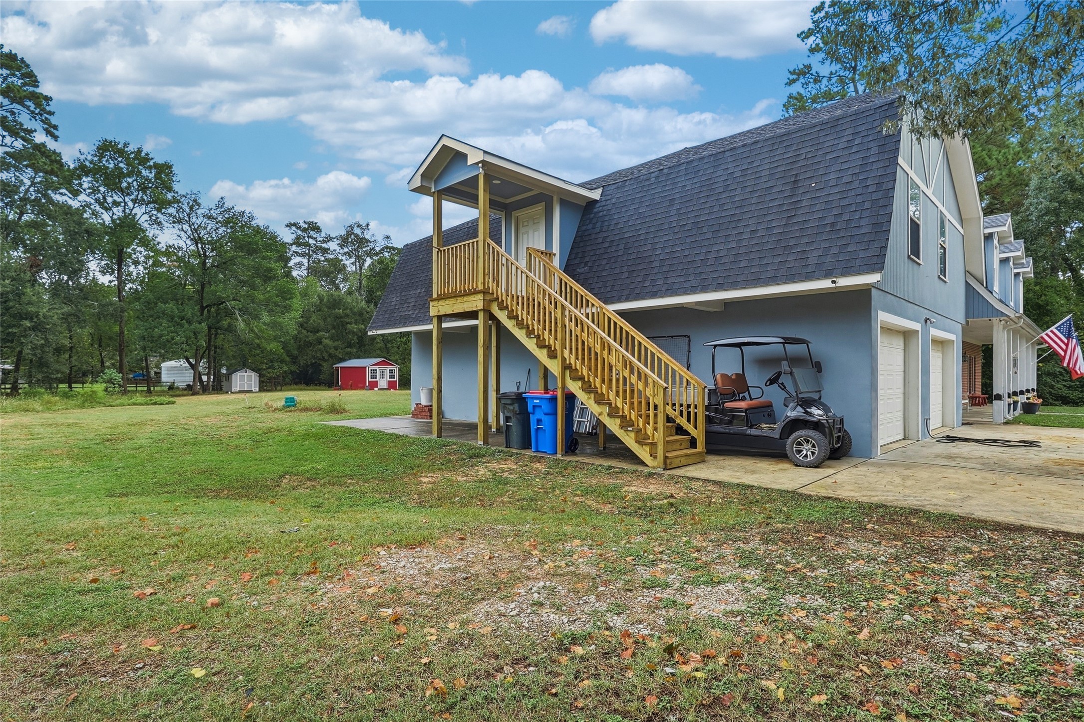 Exterior view showcasing the garage apartment entrance, set against the spacious, tree-lined side yard on two acres.