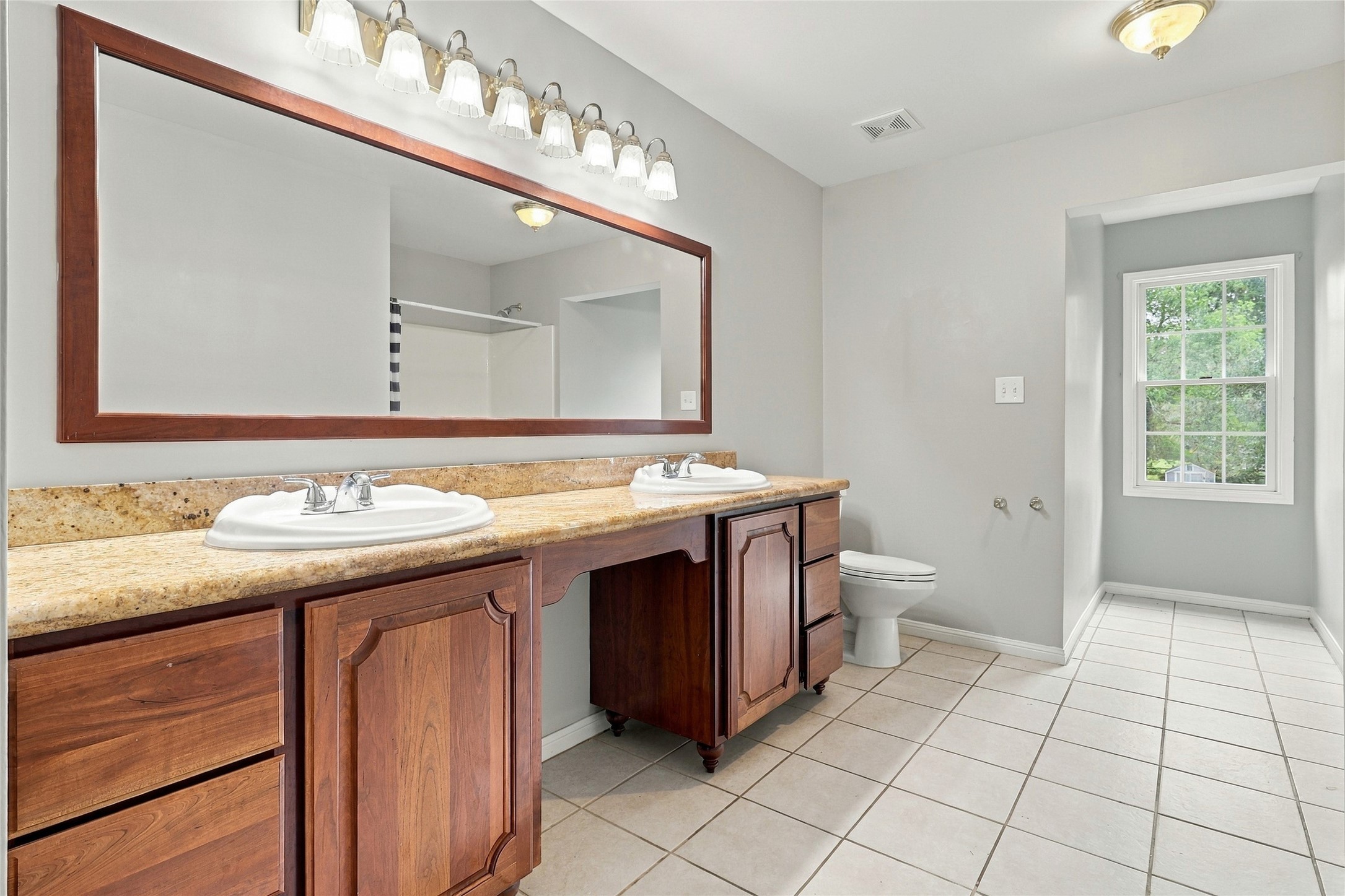 Generously sized main bath highlighted by dual sinks, vanity area, sleek updated lighting, and a newly updated mirror.