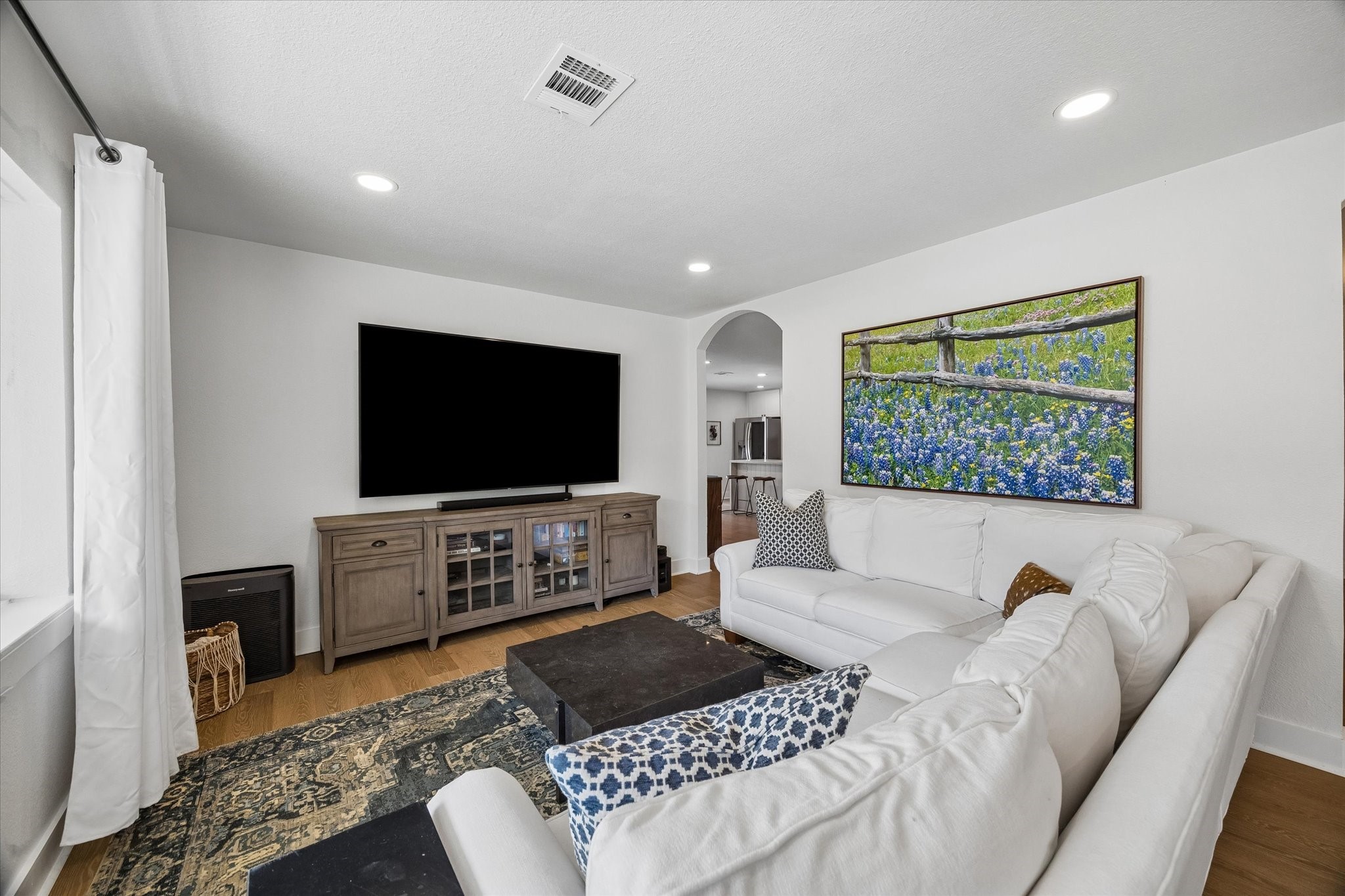 Natural light fills the spacious living room, complemented by recessed lighting, wood flooring and plenty of room to gather or unwind.