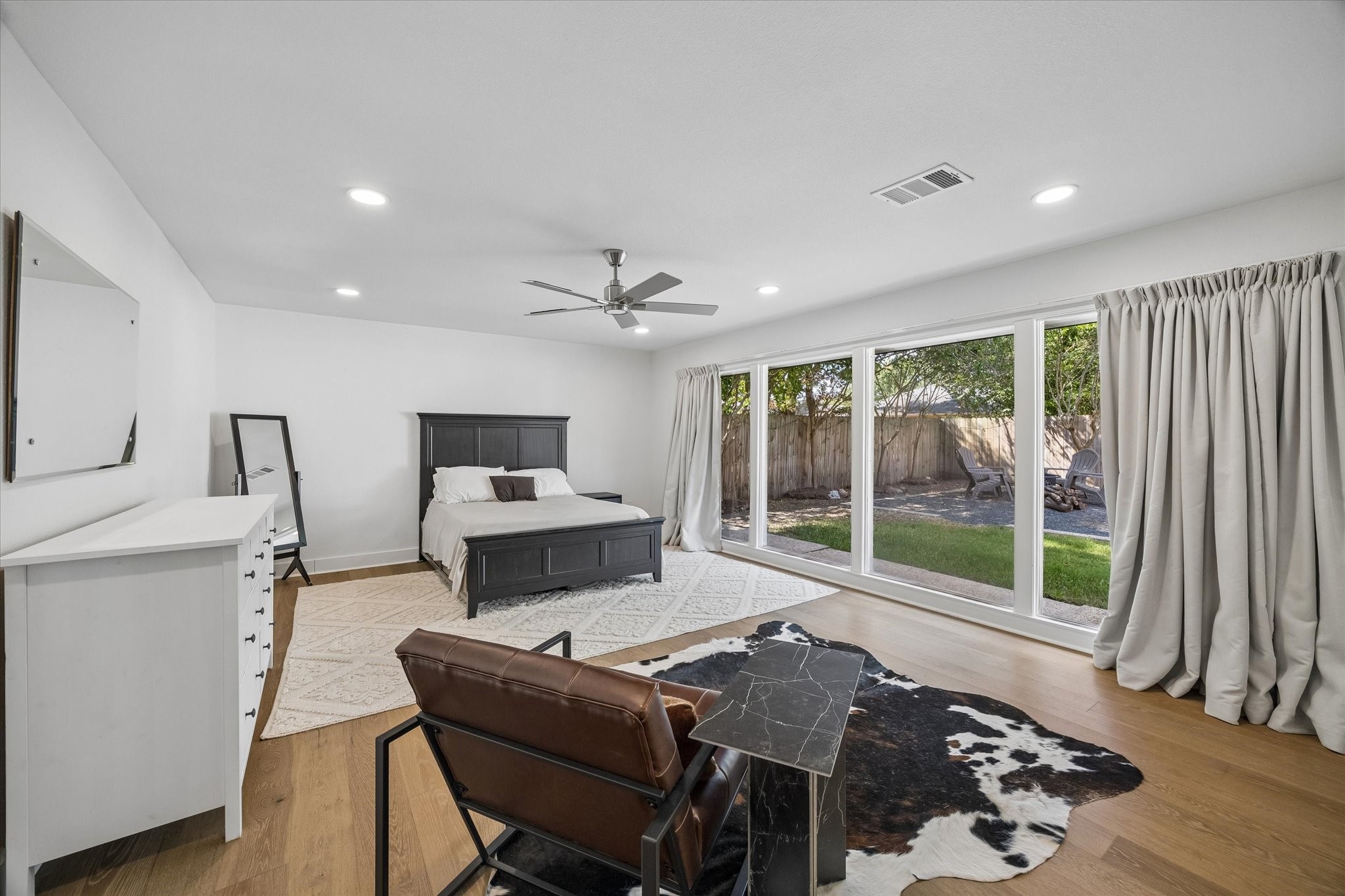 An impressive wall of windows stretches across the primary suite, filling the oversized retreat with natural light while framing views of the backyard.
