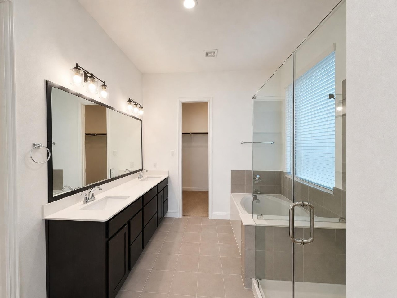 Primary suite includes a separate garden tub and shower, double sinks, a privacy door on the commode, and a large walk in closet.