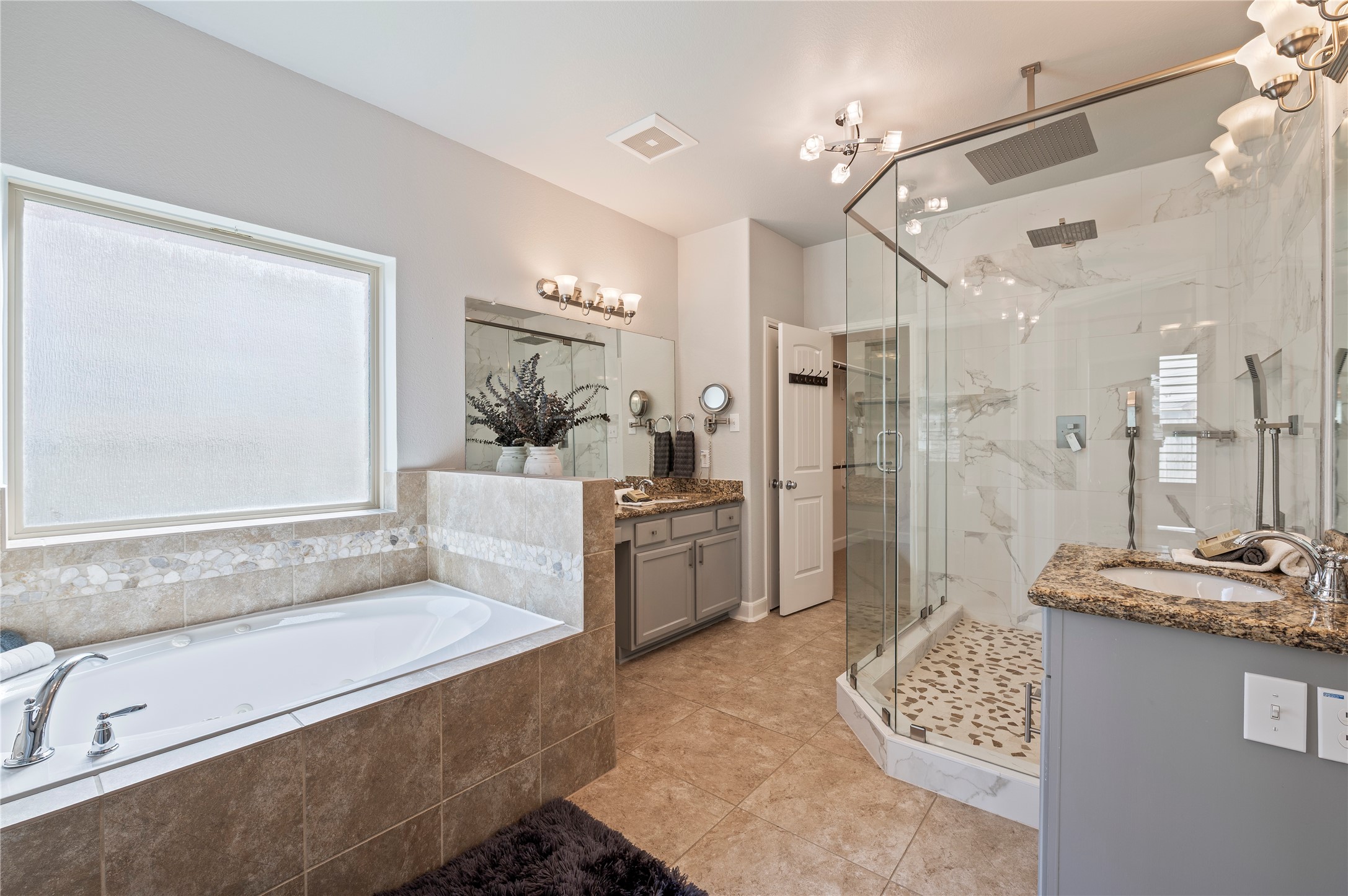Primary bathroom featuring a jetted soaking tub, updated shower, and dual vanities.  Ceramic tile and grout recently professional cleaned upon seller's move out.