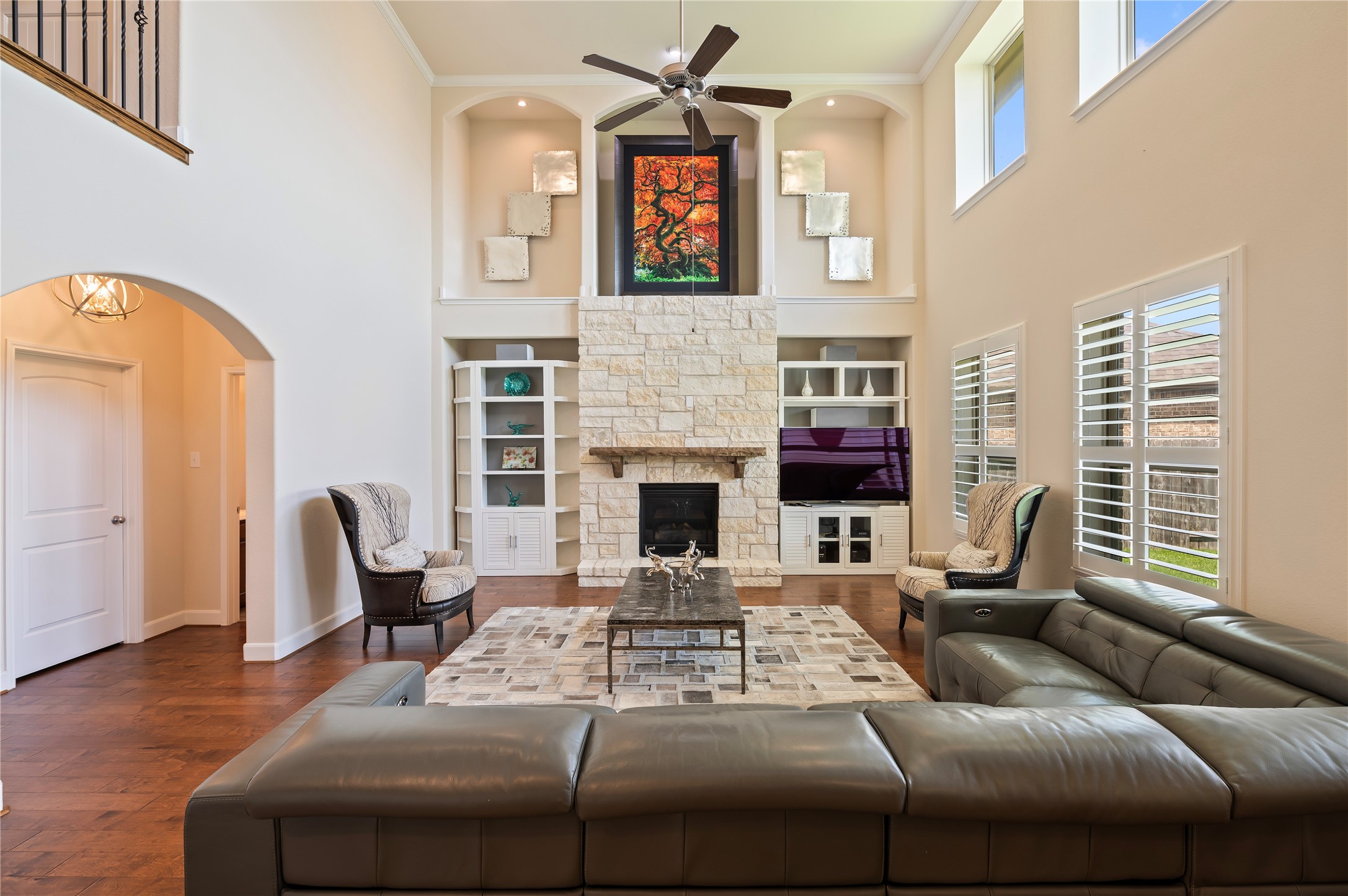 The stacked stone remote gas fireplace is the focal point of the family room with crown molding and art niches, while plantation shutters provide classic style and privacy.