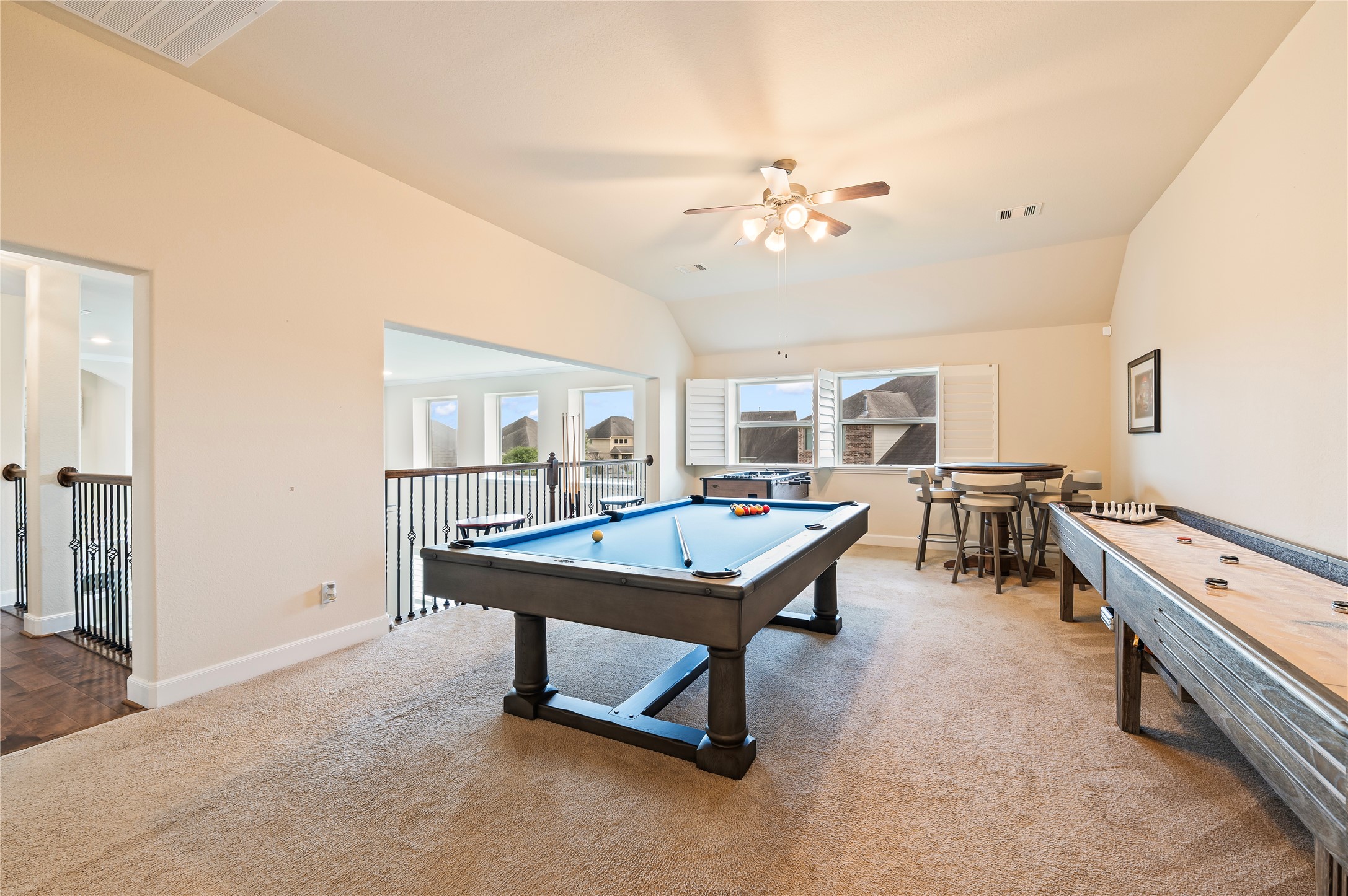 Large gameroom accented by wrought iron spinals overlooking the family room; plantation shutters and neutral paint tones.