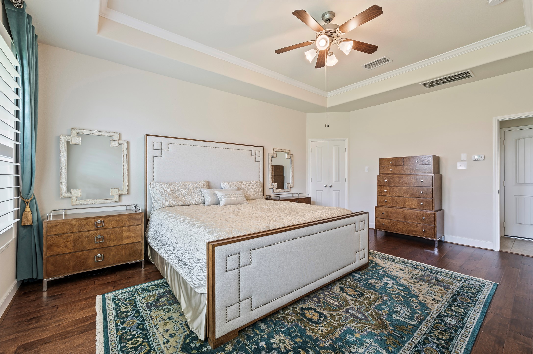 Another view of the primary suite with double doors leading to the primary bathroom and trey accent ceiling.