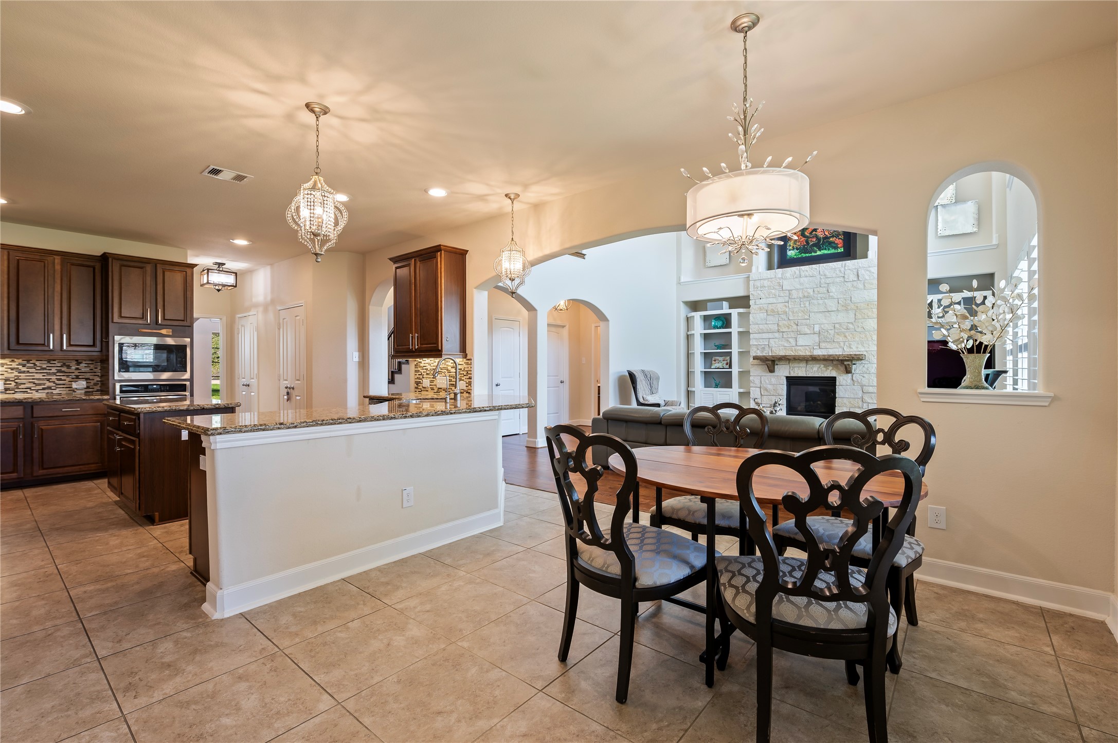 Detailed view of the open concept kitchen, breakfast and family room with custom light fixtures and plantation shutters.