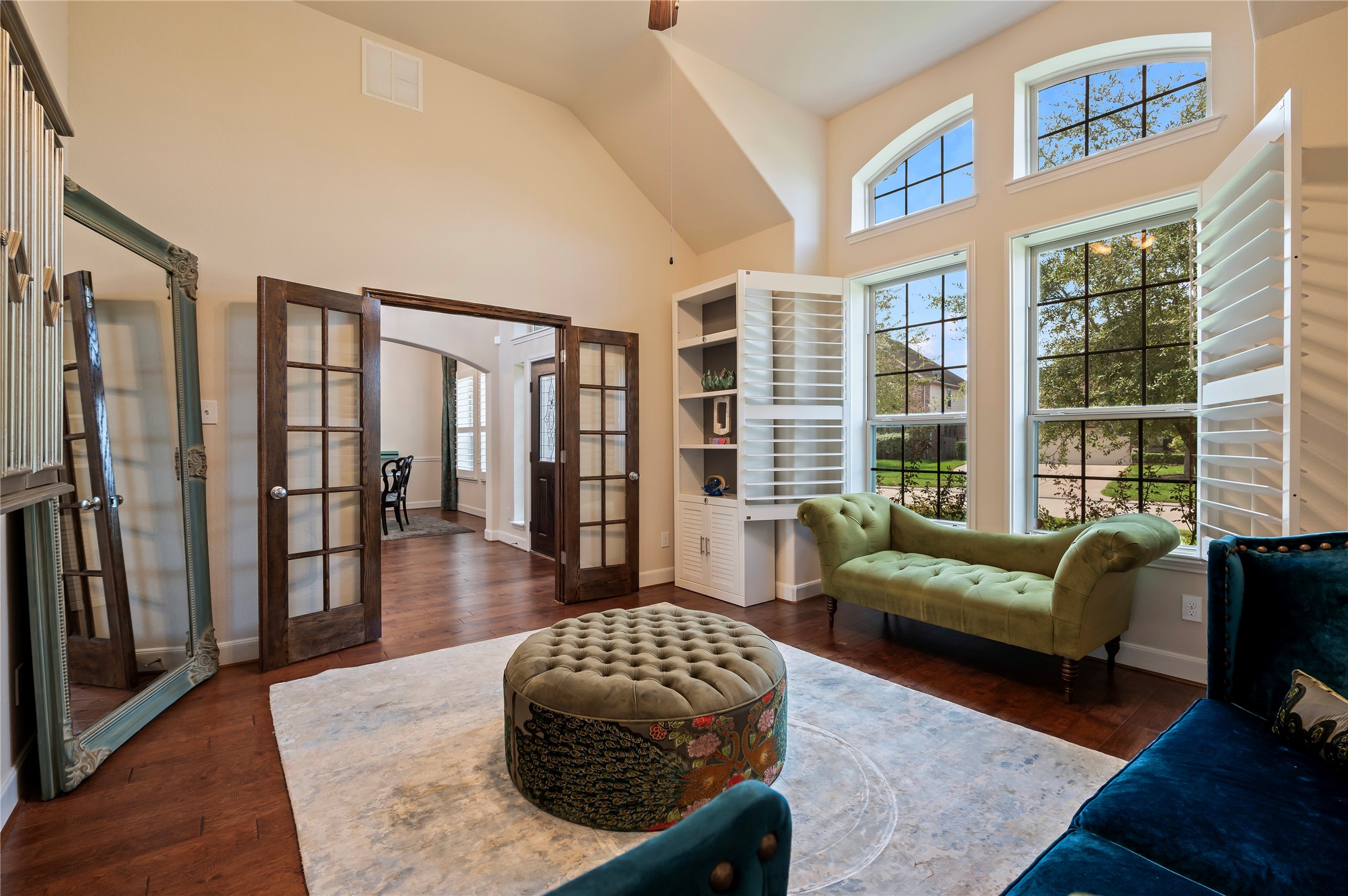 Rich stained wood French doors introduce an elegant private home office with hardwood floors and plantation shutters.