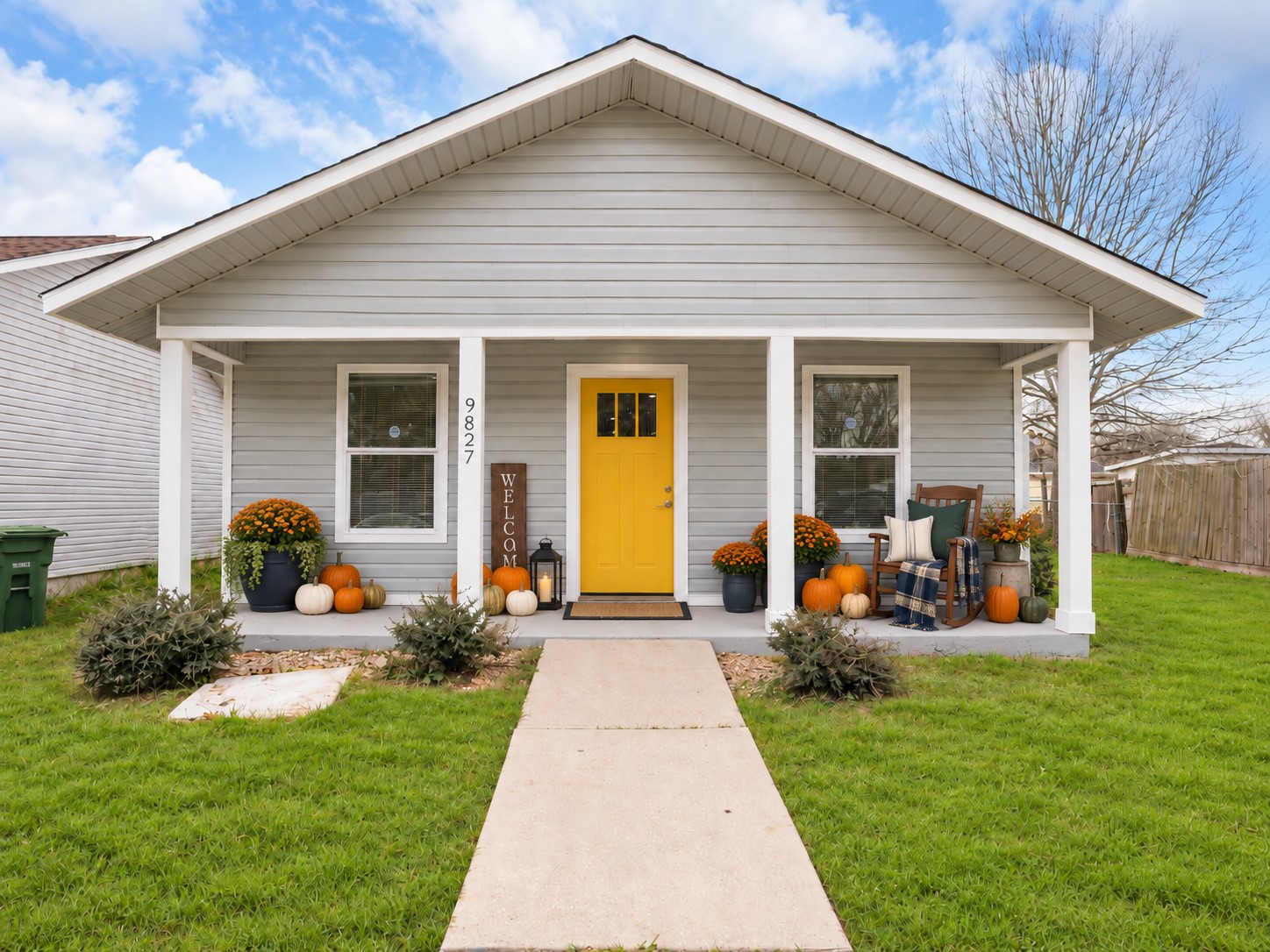 A cheerful yellow front door welcomes you to the covered porch. Digitally staged.