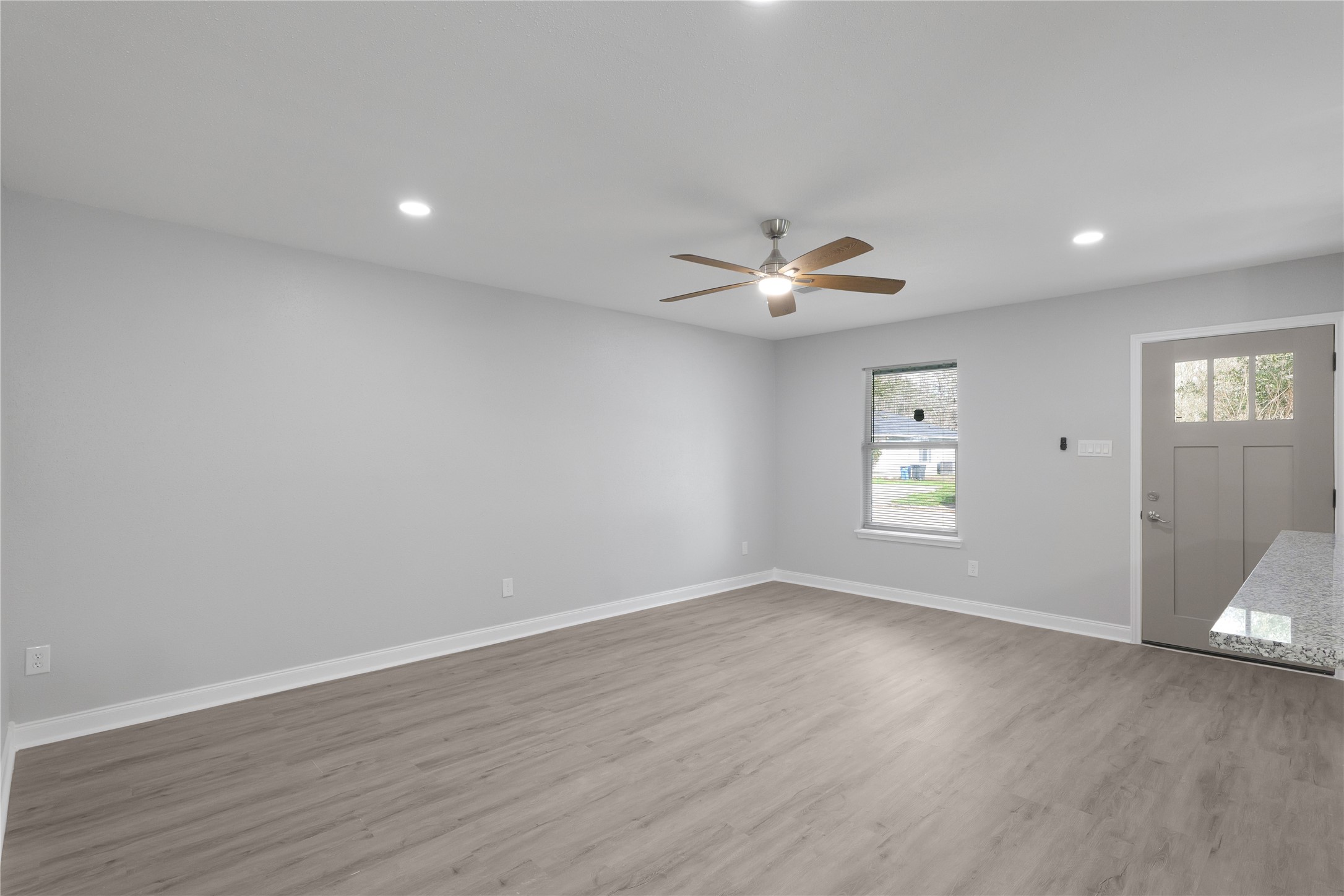Fresh neutral finishes, LVP flooring, recessed lighting, and a ceiling fan create an inviting living space.