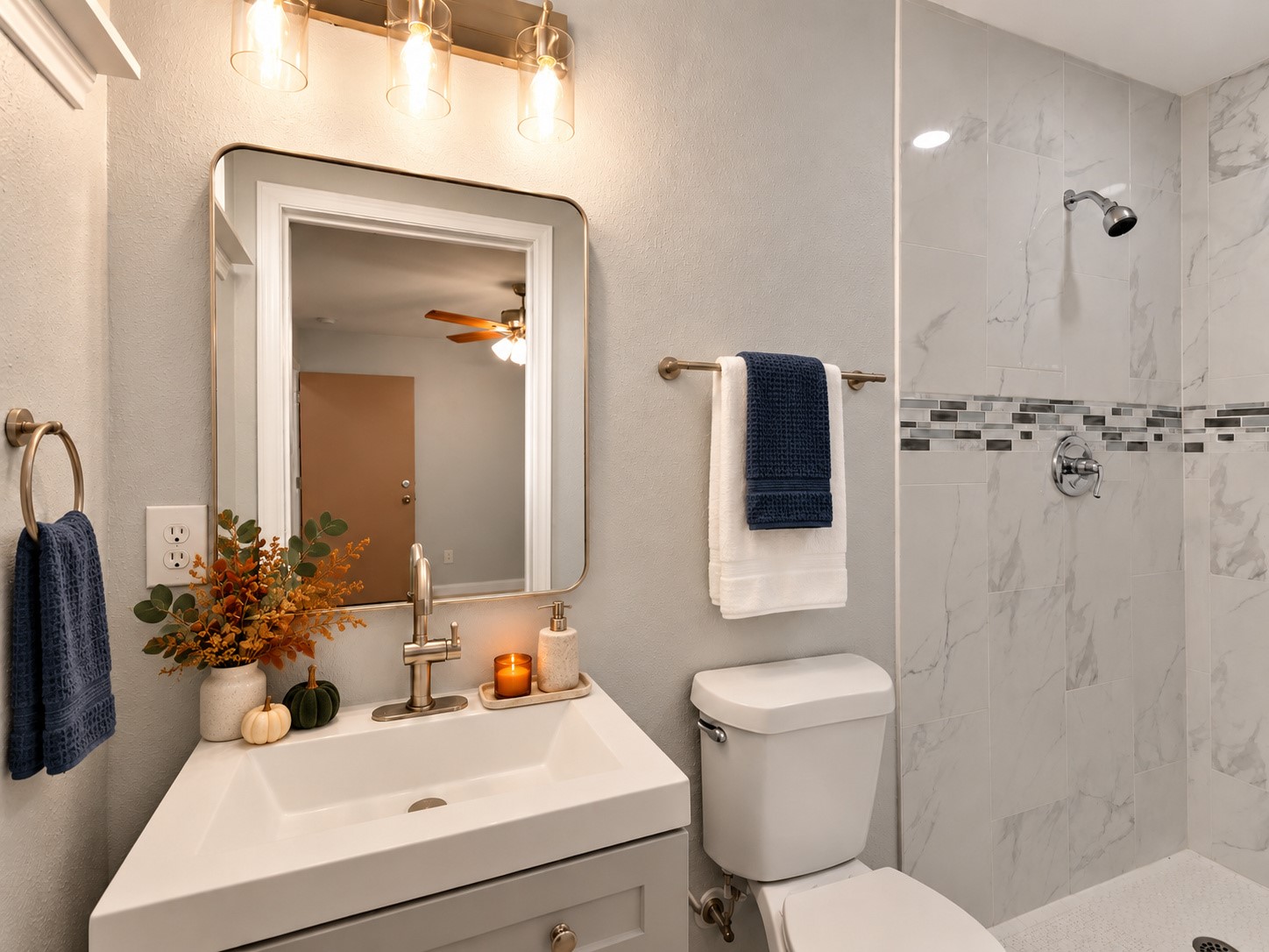 Updated bathroom featuring a tiled walk-in shower with a decorative accent, a modern vanity, and framed mirror. Digitally staged.