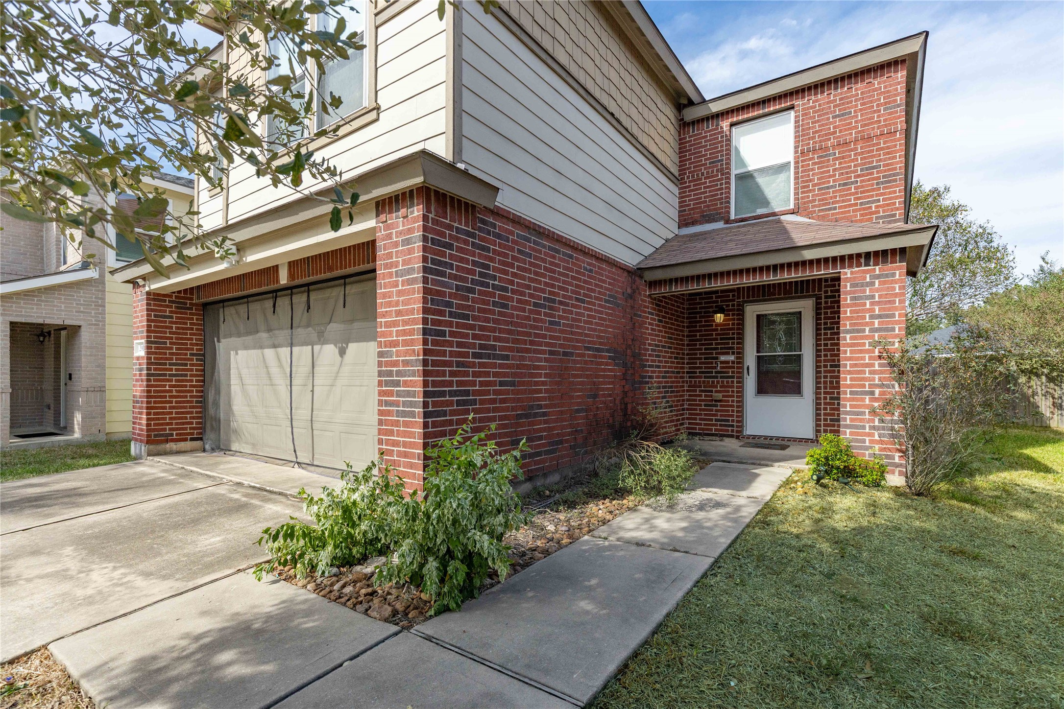 Charming two-story home featuring a combination of brick and siding exterior, with a welcoming front entrance and attached garage.